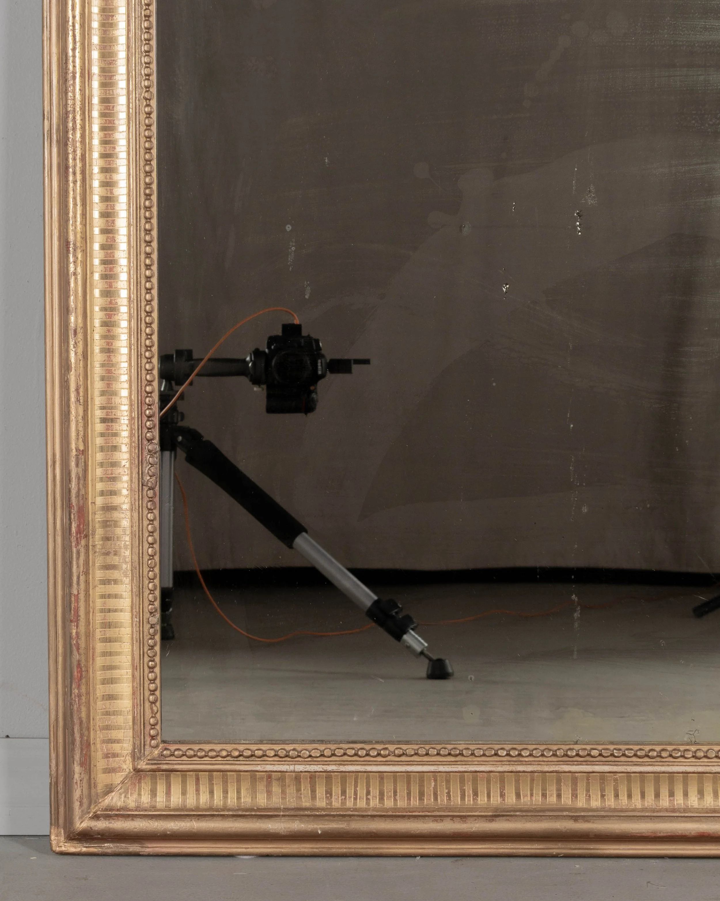 A 19th century French Louis Philippe style gilded mirror with curved top corners, incised ribbed decoration and inner bead border. Warm gilt finish with red under rub exposed.