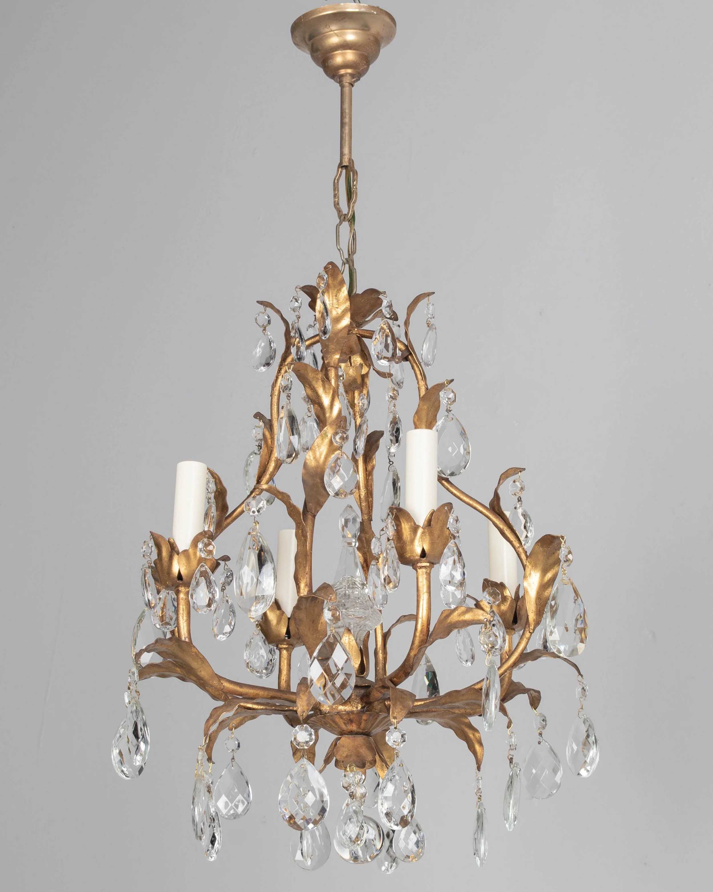StAn Italian Hollywood Regency style four-light gilt metal chandelier with tôle leaves and crystal prisms.
