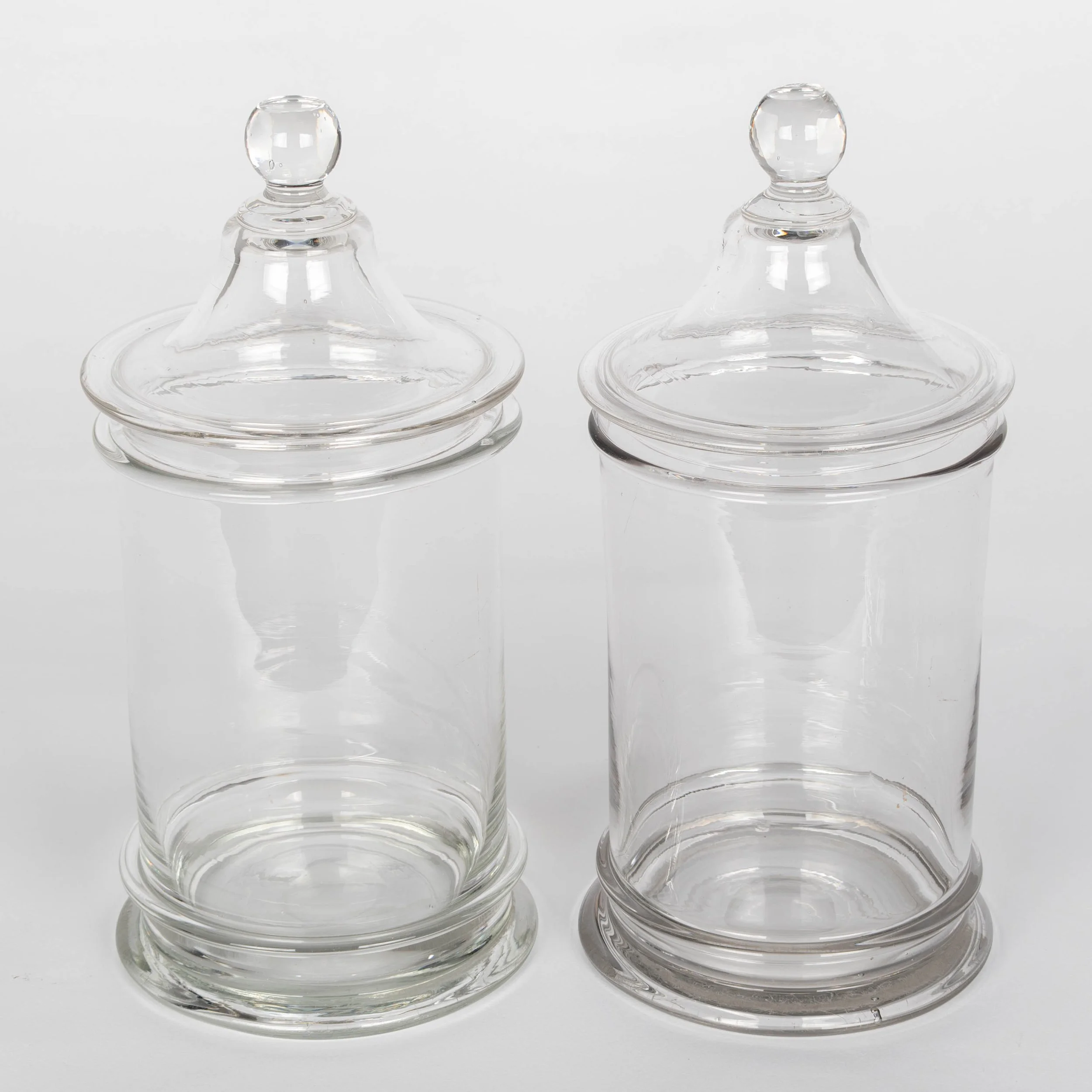 A pair of French hand-blown clear glass lidded apothecary or candy jars