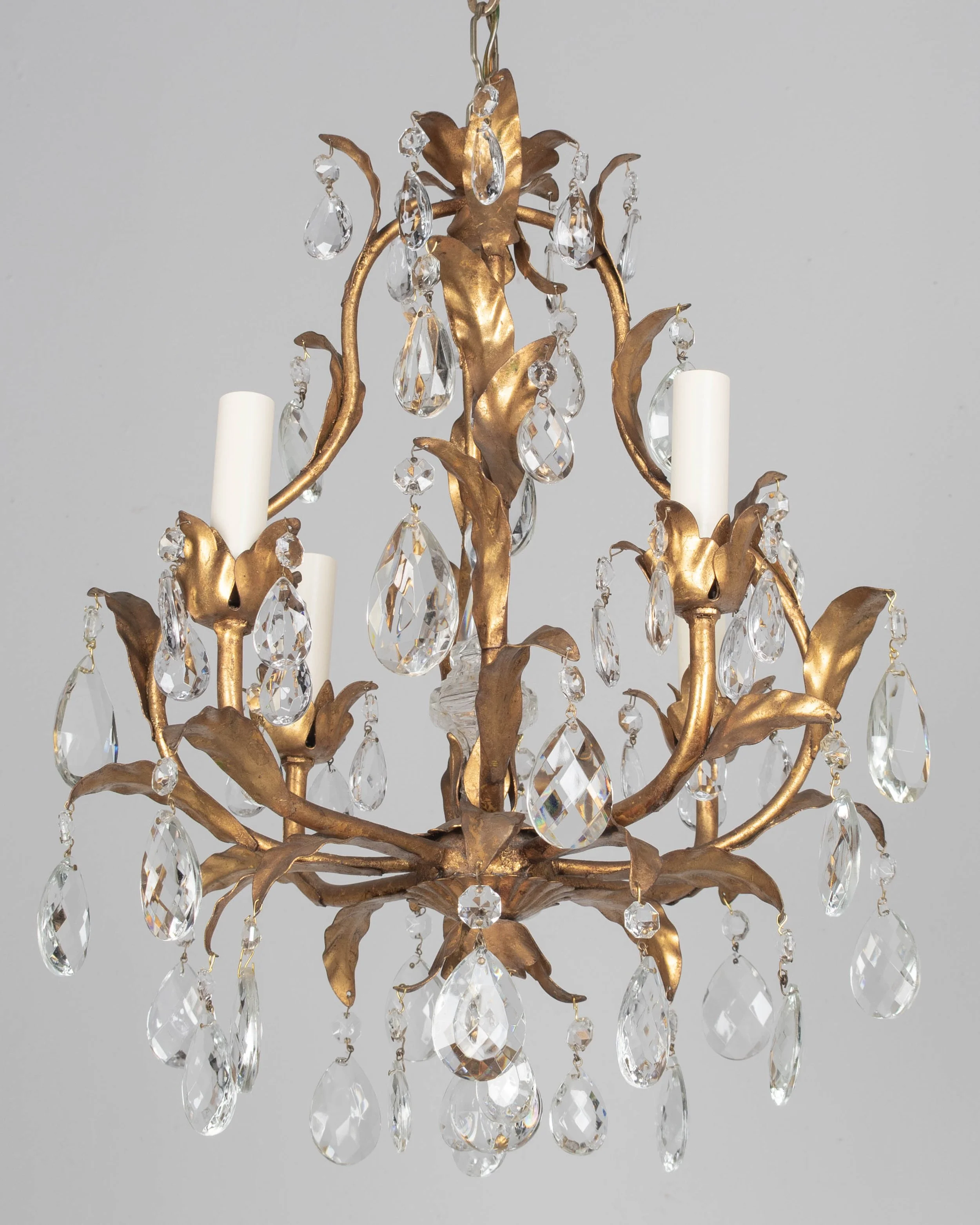 An Italian Hollywood Regency style four-light gilt metal chandelier with tôle leaves and crystal prisms.