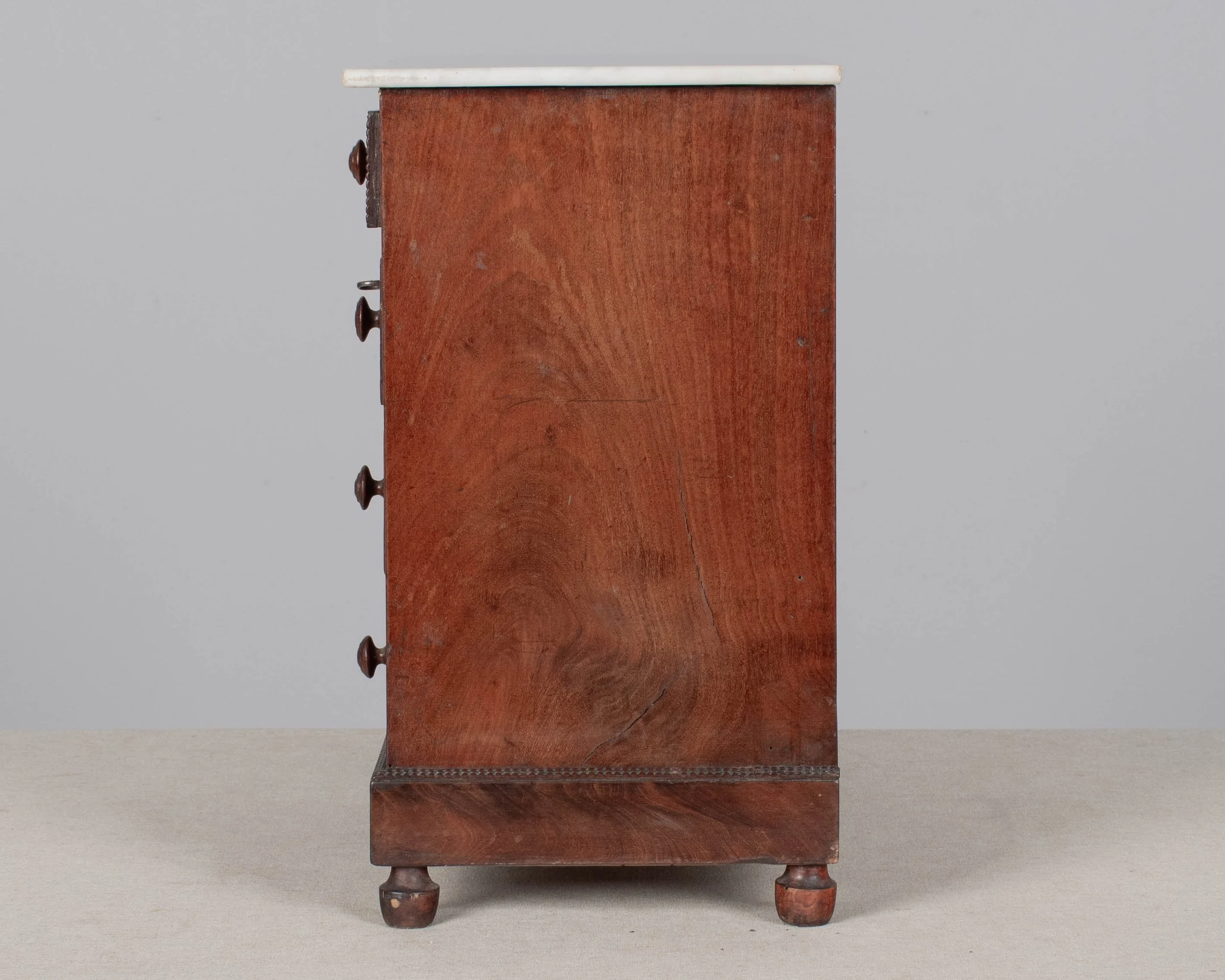 A 19th century Louis Philippe miniature sample commode made of mahogany with French polish finish. Four dovetailed drawers with turned knobs and escutcheons