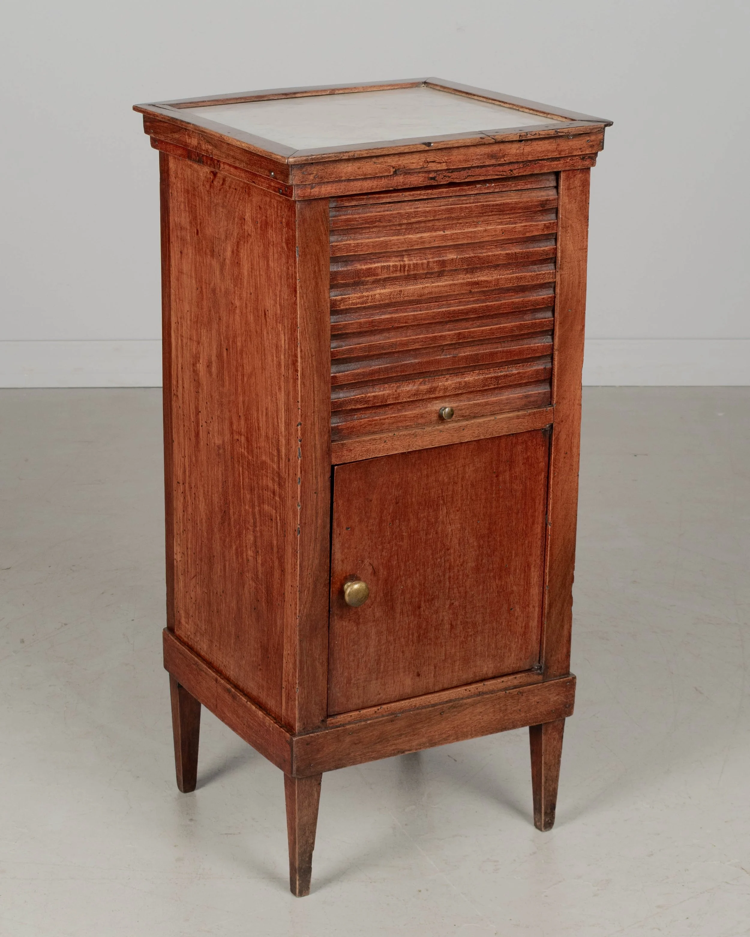 A 19th century French Country walnut side table, or nightstand, with a vertical tambour door above a cabinet door