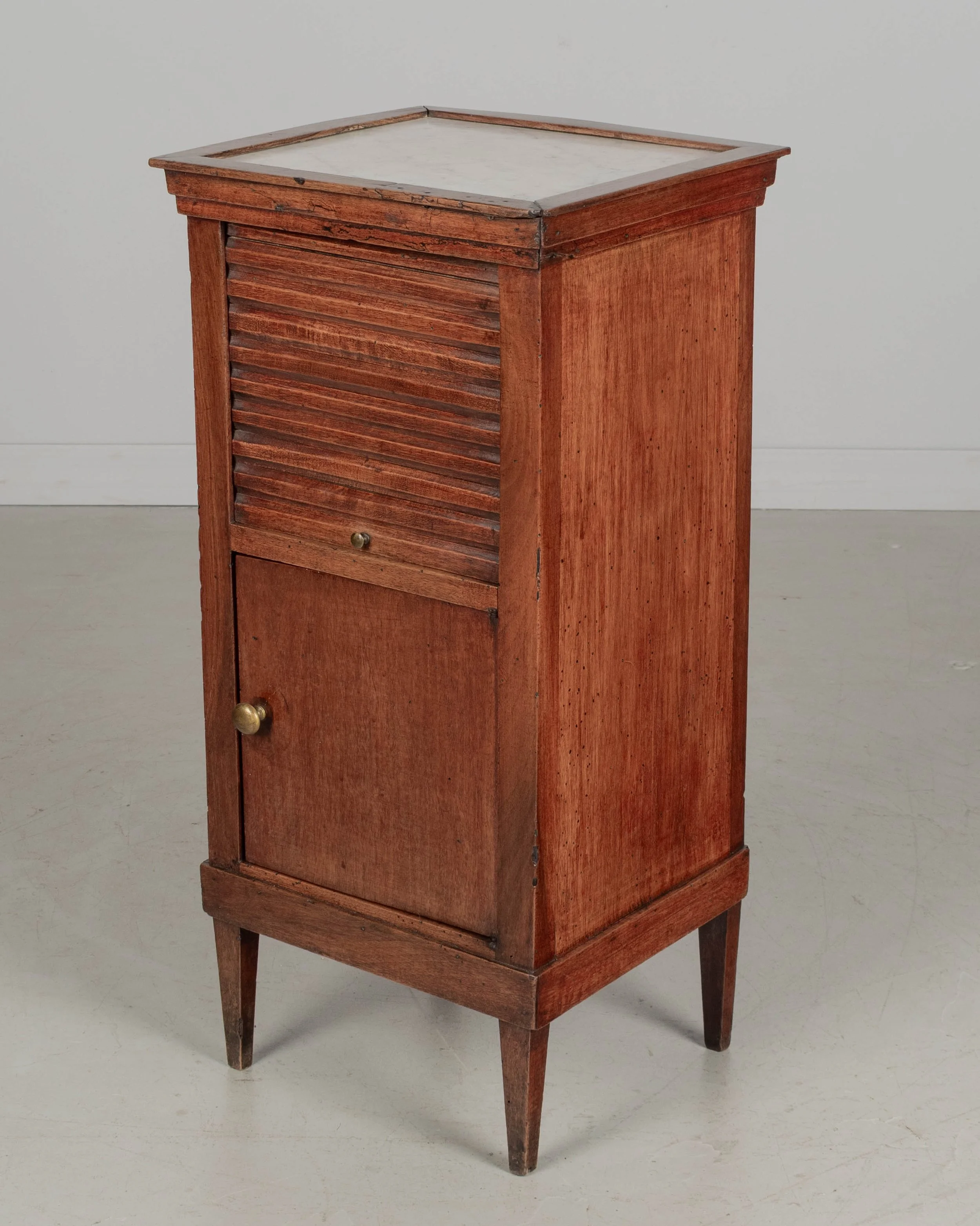 A 19th century French Country walnut side table, or nightstand, with a vertical tambour door above a cabinet door