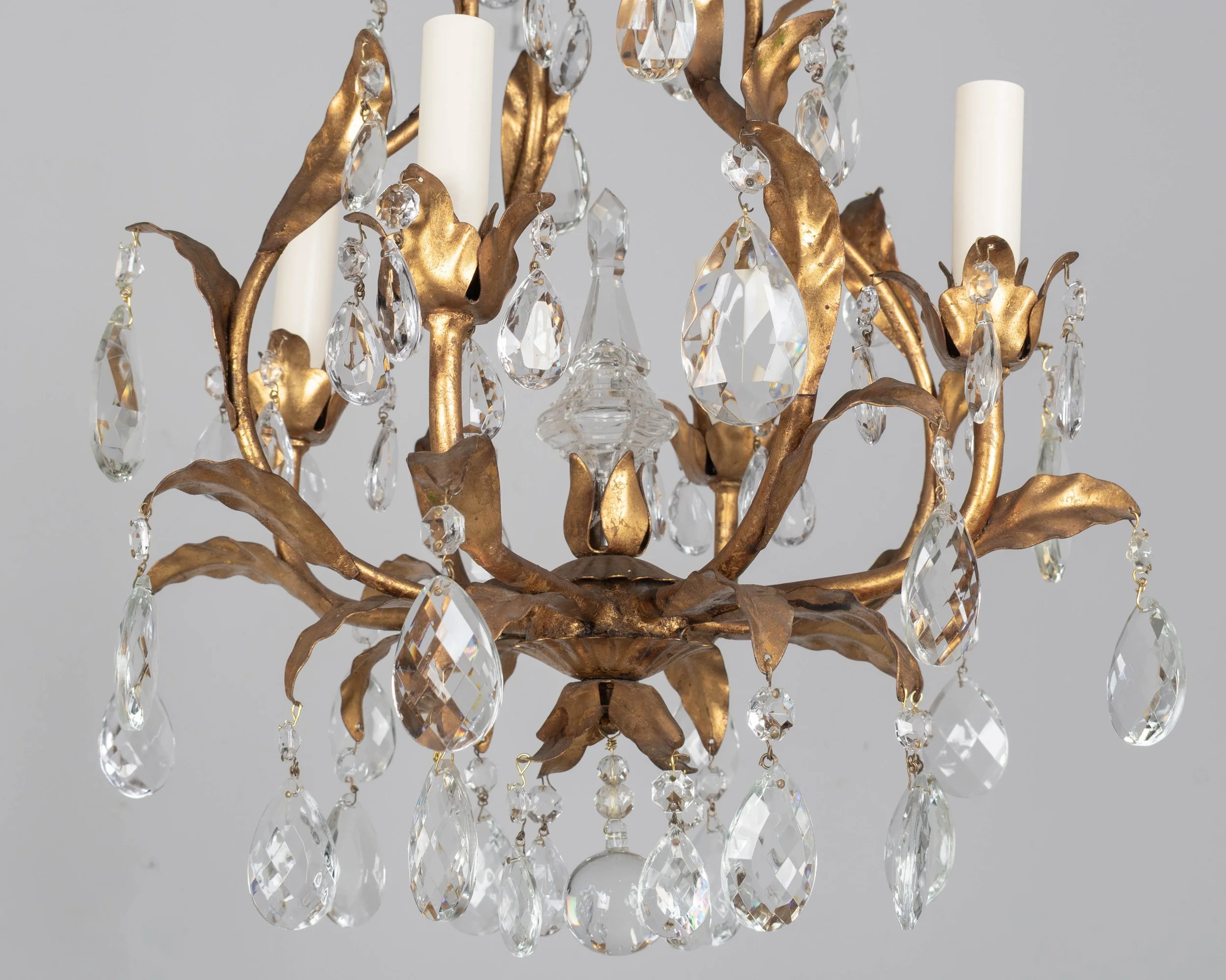 An Italian Hollywood Regency style four-light gilt metal chandelier with tôle leaves and crystal prisms.