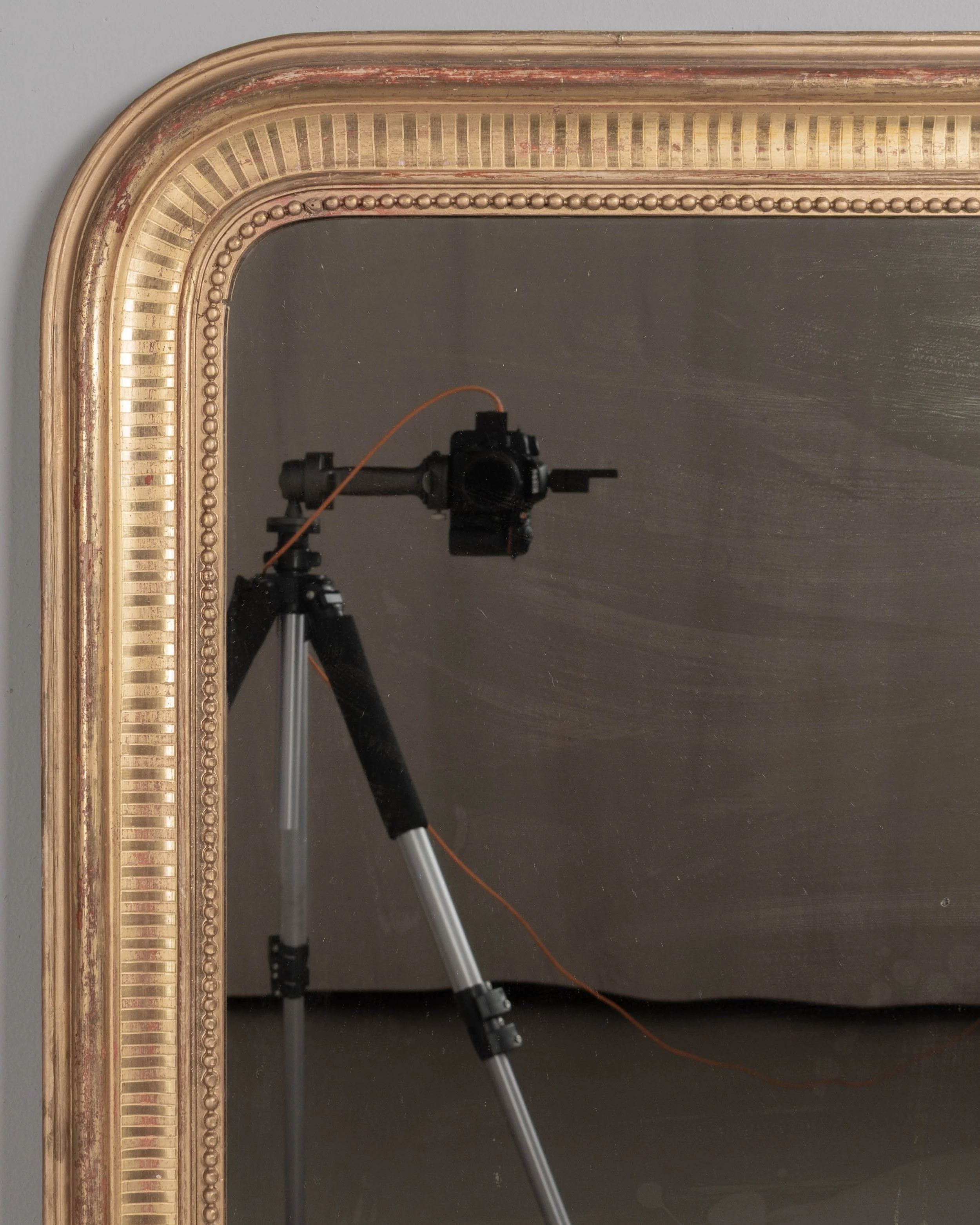 A 19th century French Louis Philippe style gilded mirror with curved top corners, incised ribbed decoration and inner bead border. Warm gilt finish with red under rub exposed.