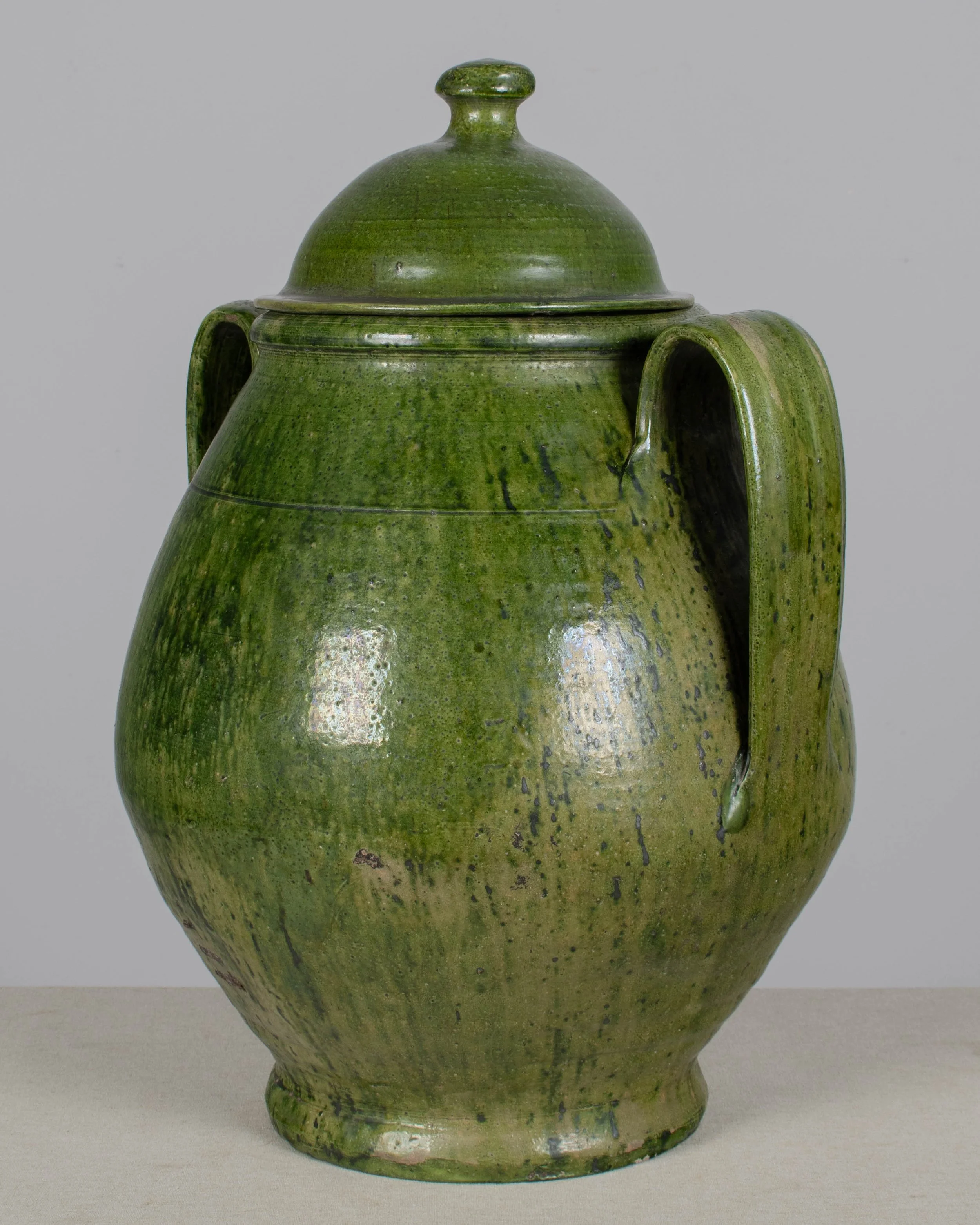 A large green glazed earthenware lidded jar made in Portugal