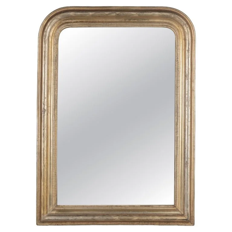 A French Louis Philippe style gilded mirror with curved top corners and incised floral decoration.