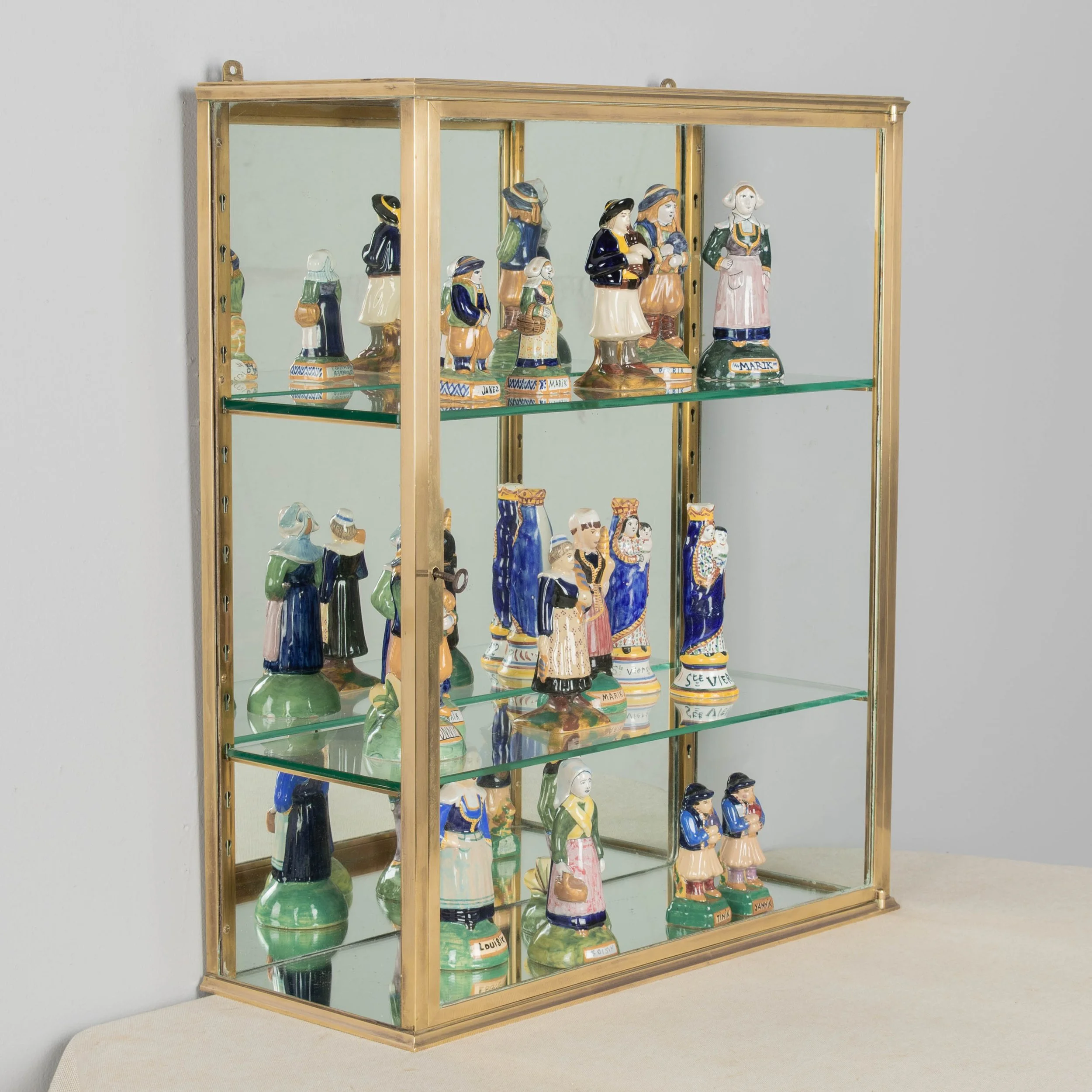 A French Art Deco hanging wall vitrine with solid brass frame, mirrored back and glass panes.