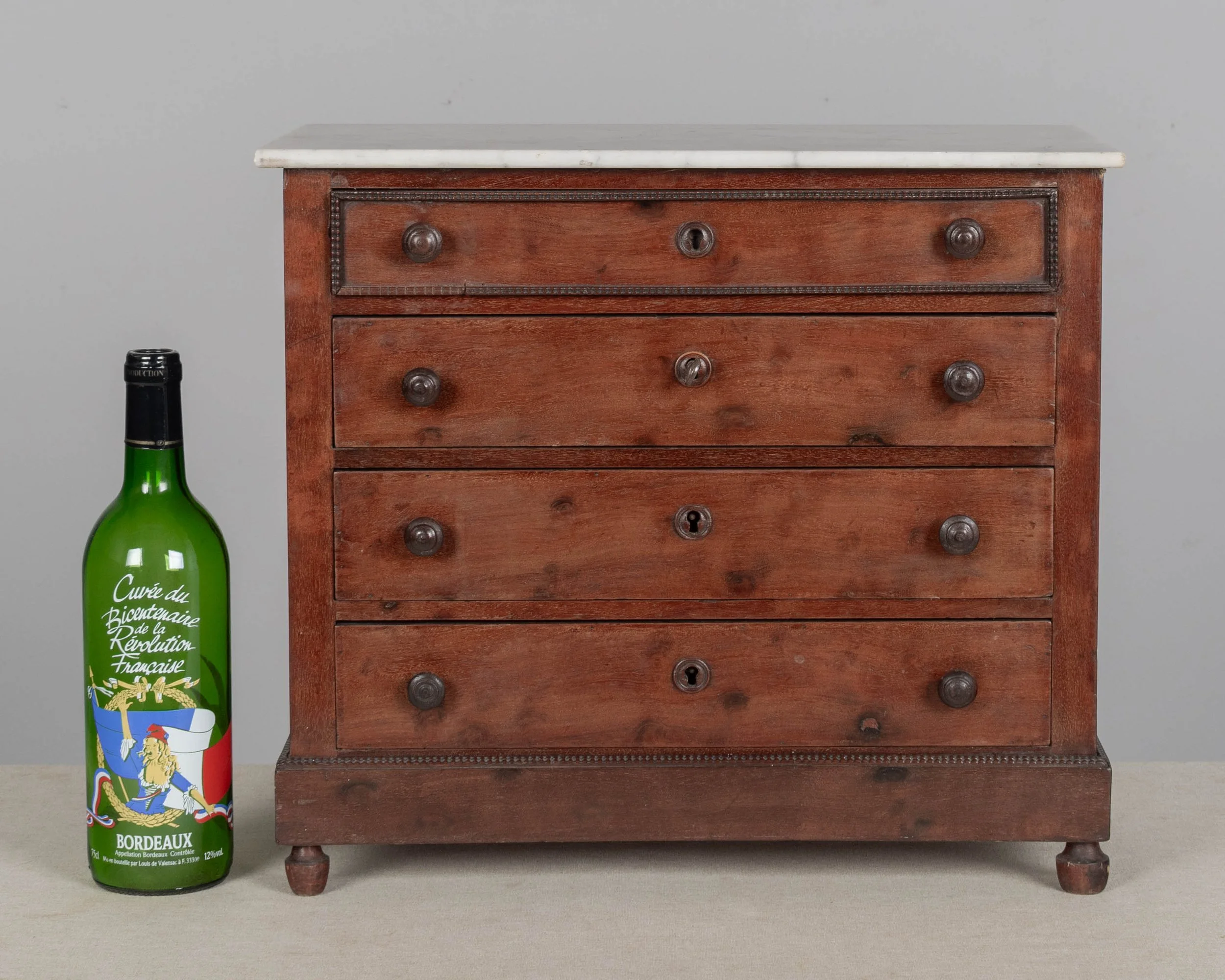 A 19th century Louis Philippe miniature sample commode made of mahogany with French polish finish. Four dovetailed drawers with turned knobs and escutcheons