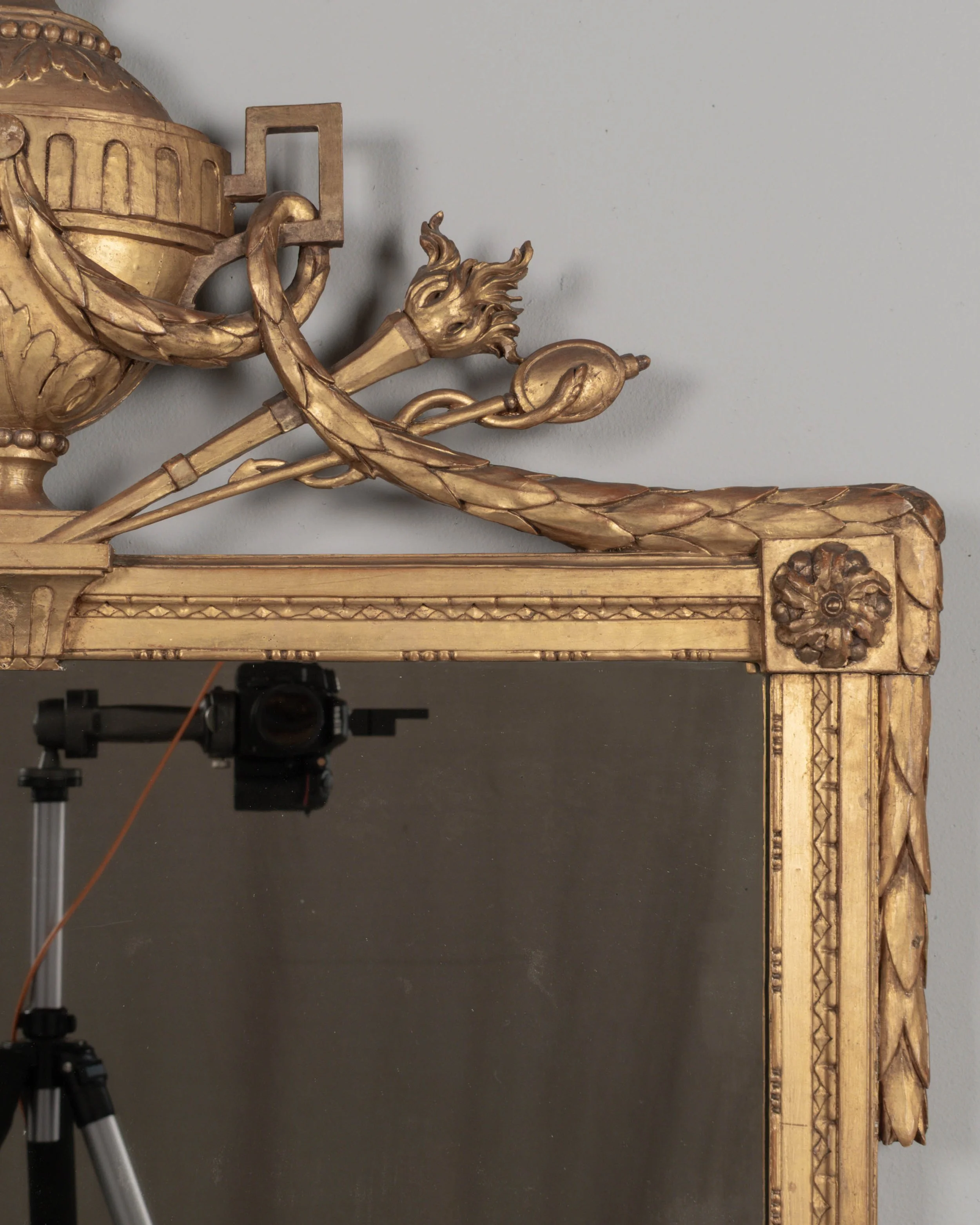 A Louis XVI style French giltwood mirror. Hand carved crest with large urn, torch, ribbons, and garlands.
