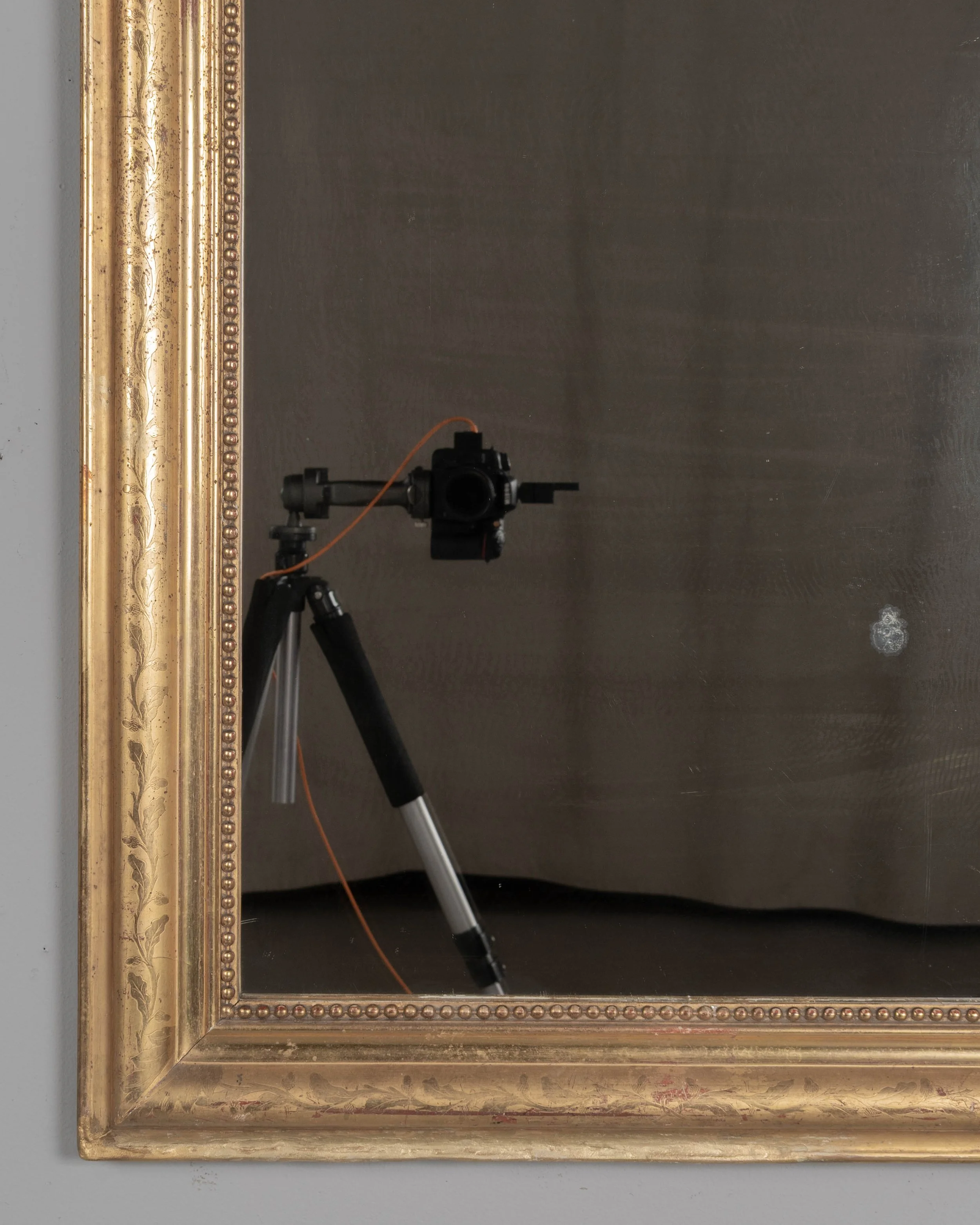 An early 20th century French Louis Philippe style gilded mirror with curved top corners, incised floral decoration and inner bead border.