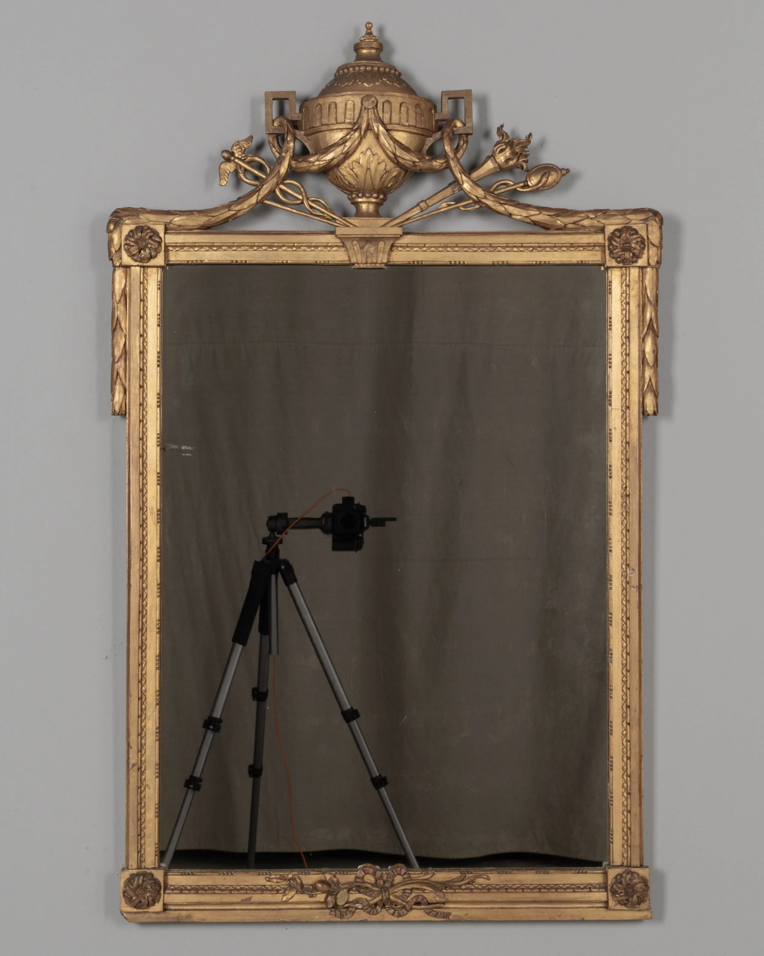 A Louis XVI style French giltwood mirror. Hand carved crest with large urn, torch, ribbons, and garlands.