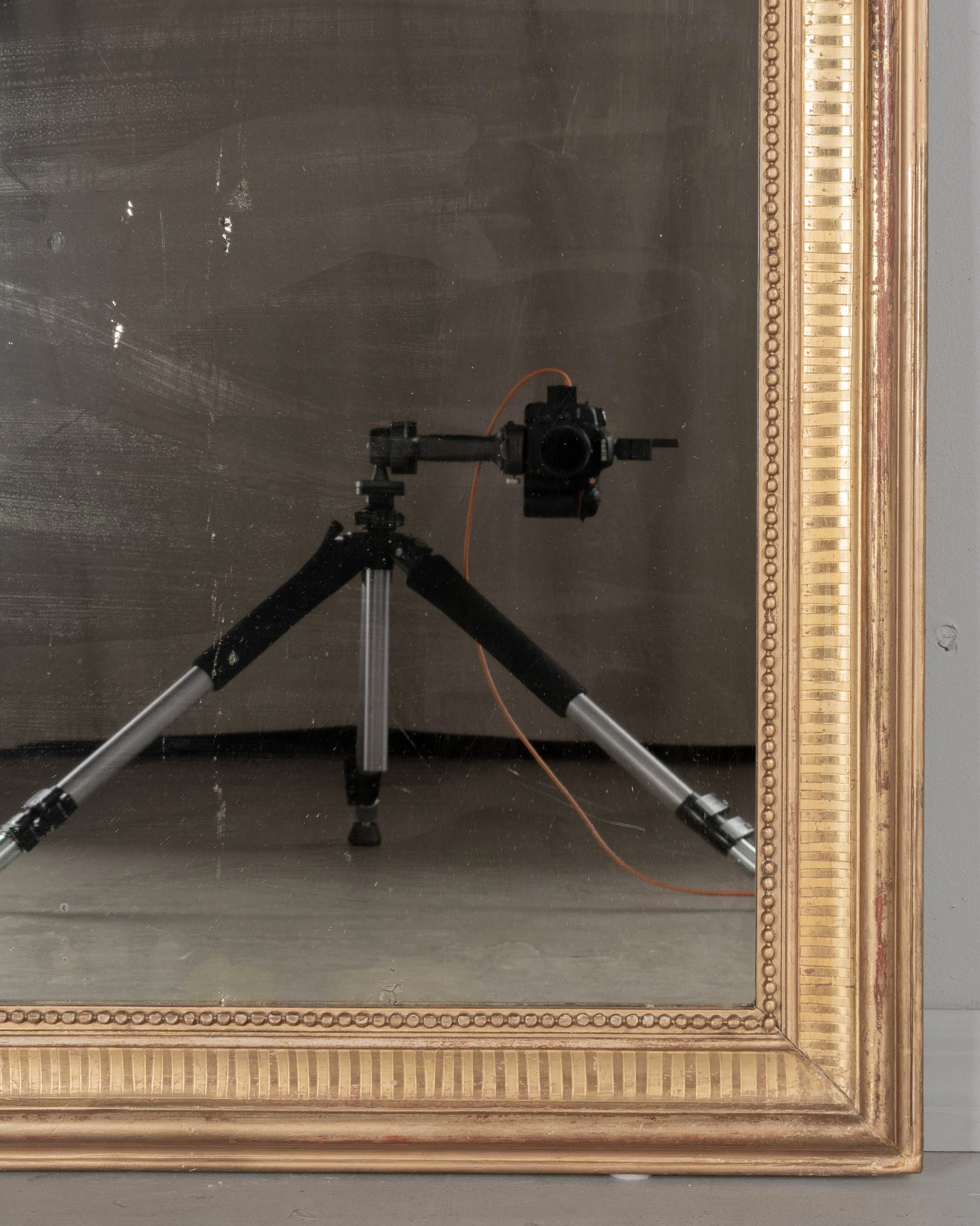 A 19th century French Louis Philippe style gilded mirror with curved top corners, incised ribbed decoration and inner bead border. Warm gilt finish with red under rub exposed.