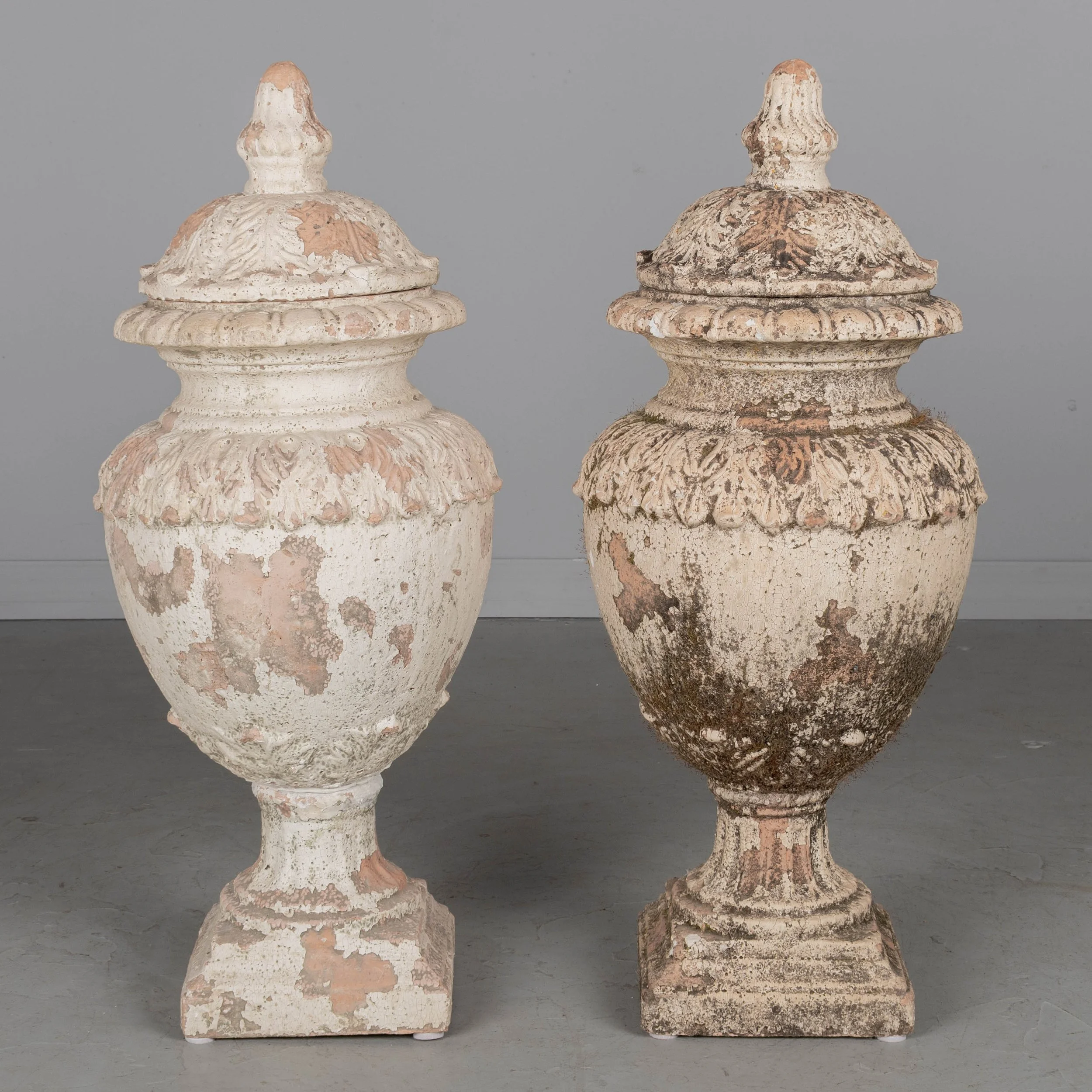 A pair of French terracotta garden urns with lids. Classical vase form on pedestal base, decorated in acanthus leaf motif with large acorn finials on lids.