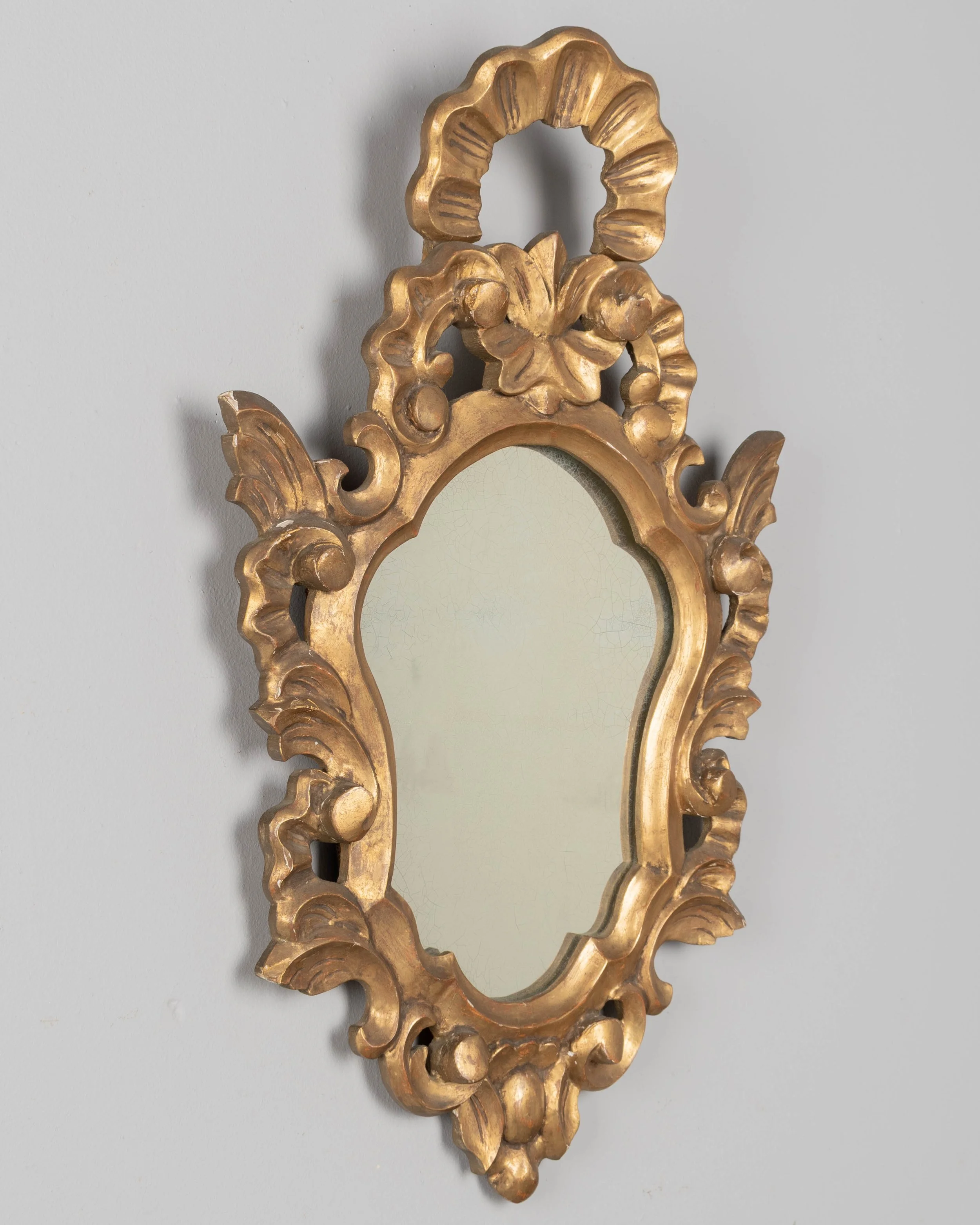 French Baroque style giltwood mirror with cartouche shape framed by undulating borders.