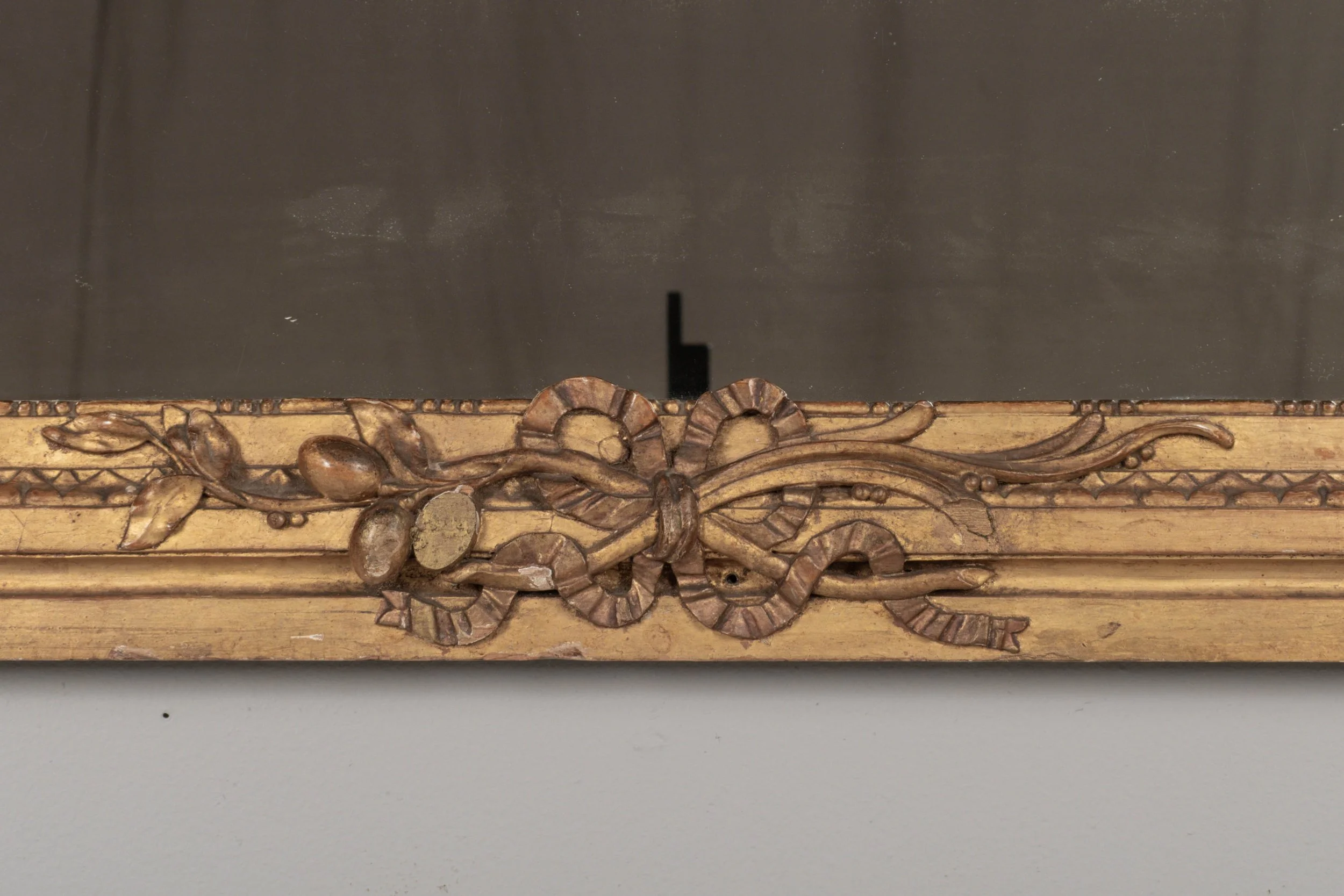 A Louis XVI style French giltwood mirror. Hand carved crest with large urn, torch, ribbons, and garlands.