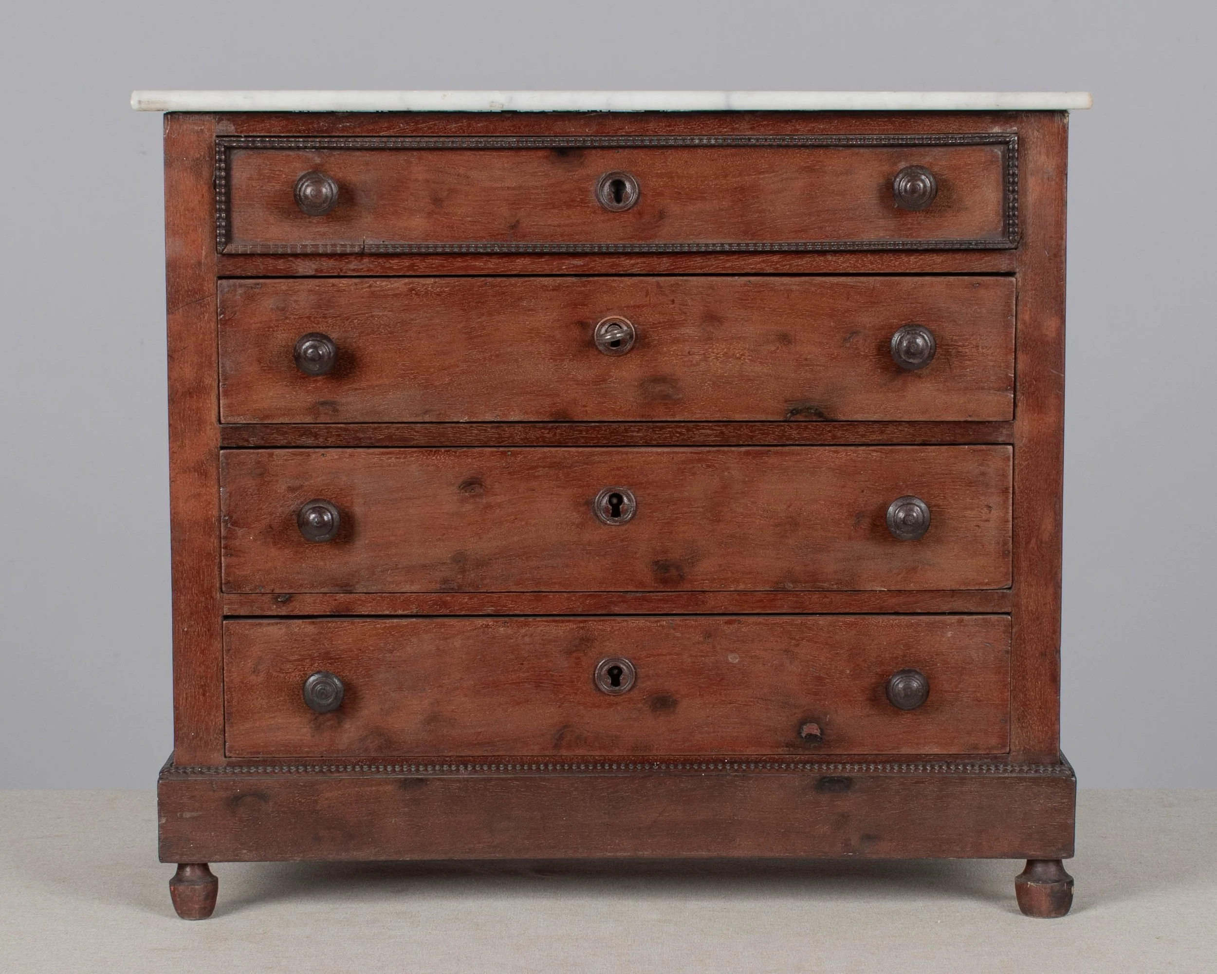 A 19th century Louis Philippe miniature sample commode made of mahogany with French polish finish. Four dovetailed drawers with turned knobs and escutcheons