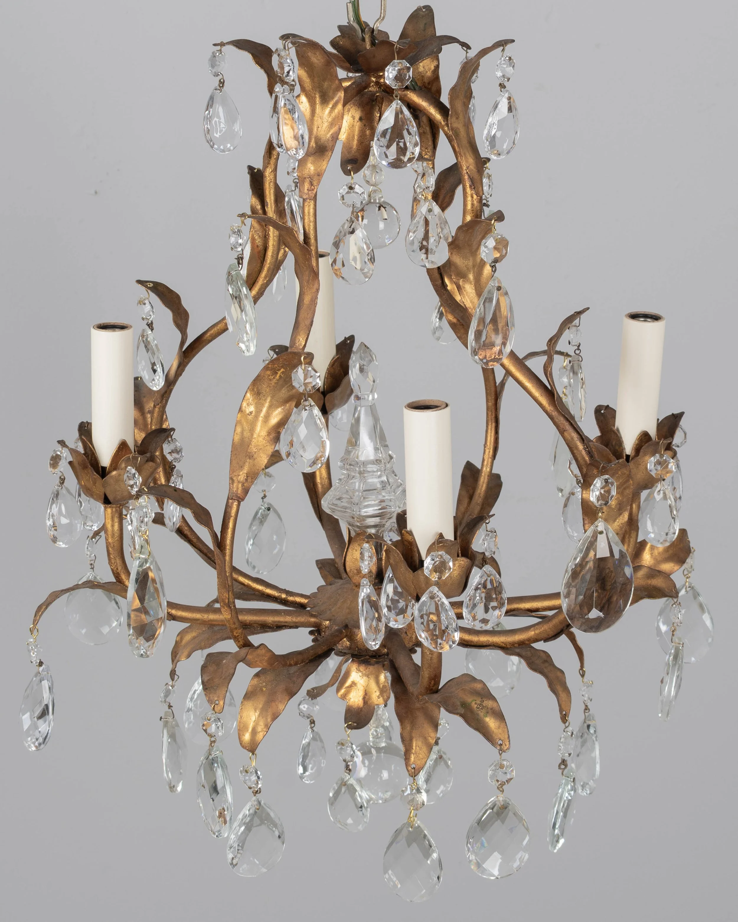 An Italian Hollywood Regency style four-light gilt metal chandelier with tôle leaves and crystal prisms.