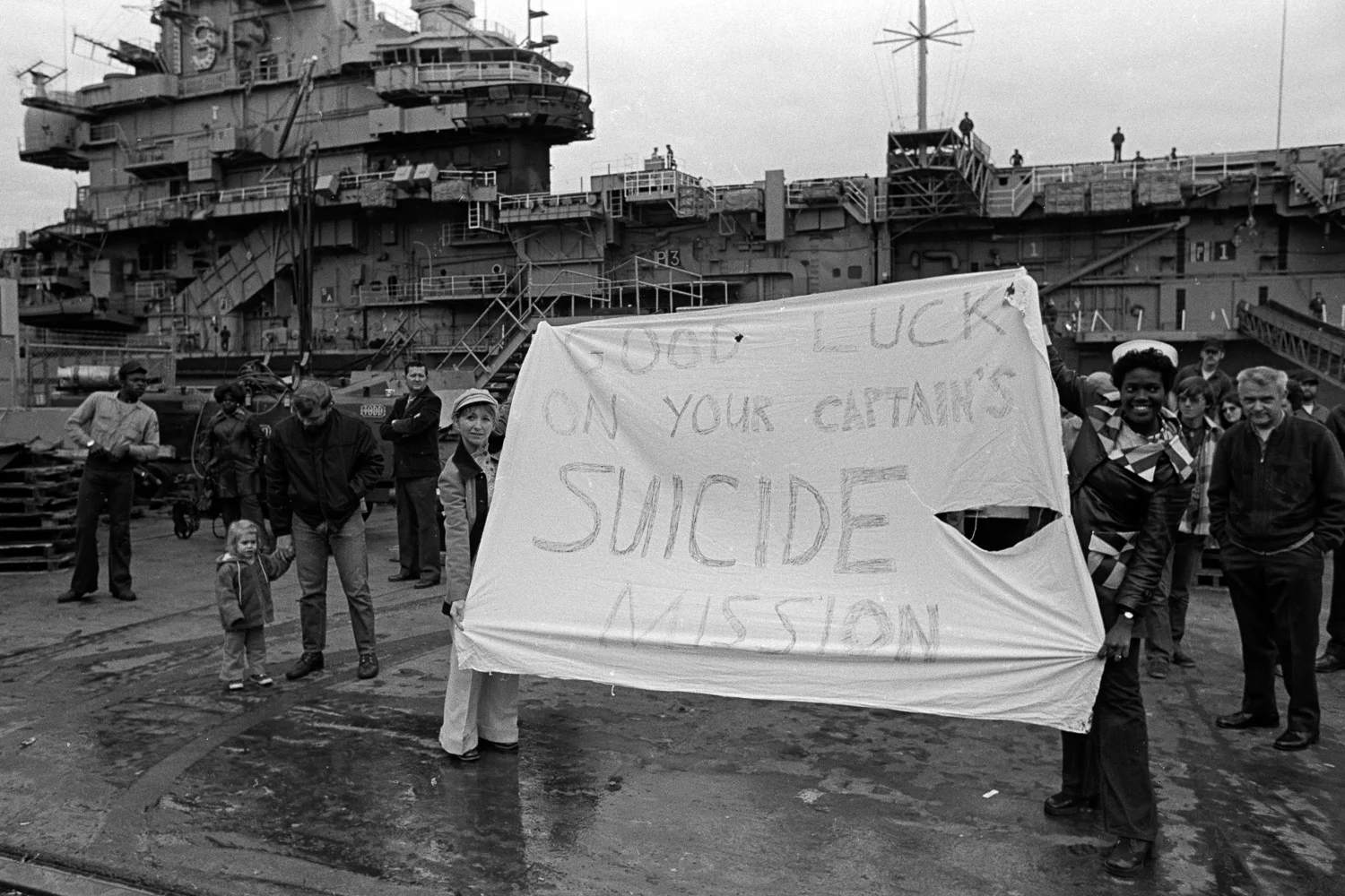 Rose Hills (right) and Vicky Kelly (right) unfurl their banner to the crewman on board the USS Coral Sea as they prepare to ship out on December 5, 1974.