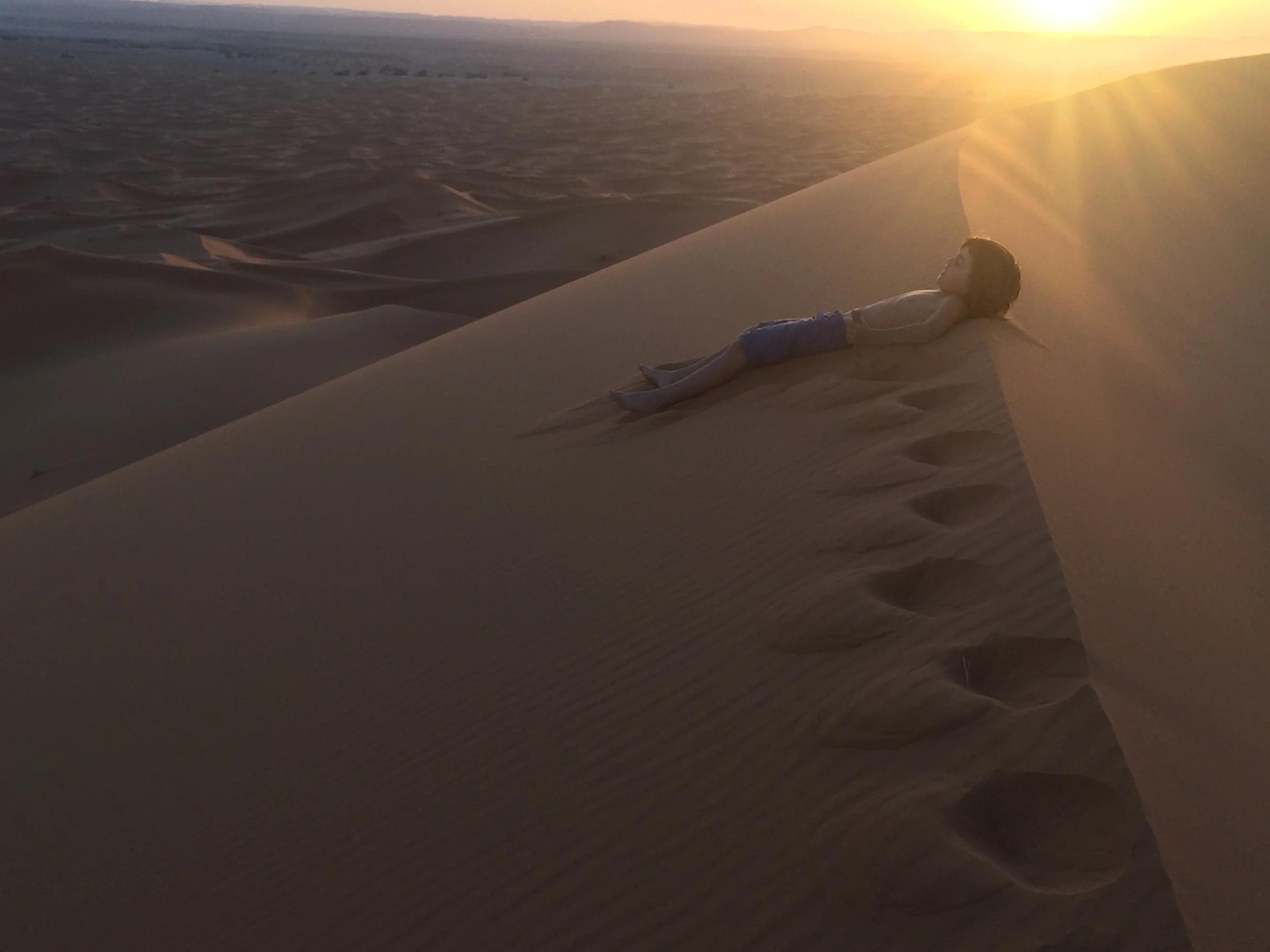We wanted to see the sunset. I wanted to run to the top and run all the way down. It was a huge mountain of sand. I had seen a desert before in egypt but that was many years ago, so I just remember it through photos. It felt fun to run - running down I actually did a big flip. I didn't hurt myself because the sand was so soft. It was also very cool in temperature. When you step you sink into the sand so you can lose balance easily. It was also very steep. My legs became numb walking up. The view was spectacular. I felt amazed. Mum and I had a big hug at the top of the dune. I wanted to hold mums hand going down and run really fast because I thought it would be fun, but mum felt a bit scared of heights so she followed all of my steps down. I ran down as fast as i could. the Sahara is a huge desert with foxes,bugs,camels and scorpions which is really fascinating because when it is winter all of animals borrow underground so they still they are warm. Sahara gets really hot at and really cold night - this makes it a harsh environment for animals and plants. 