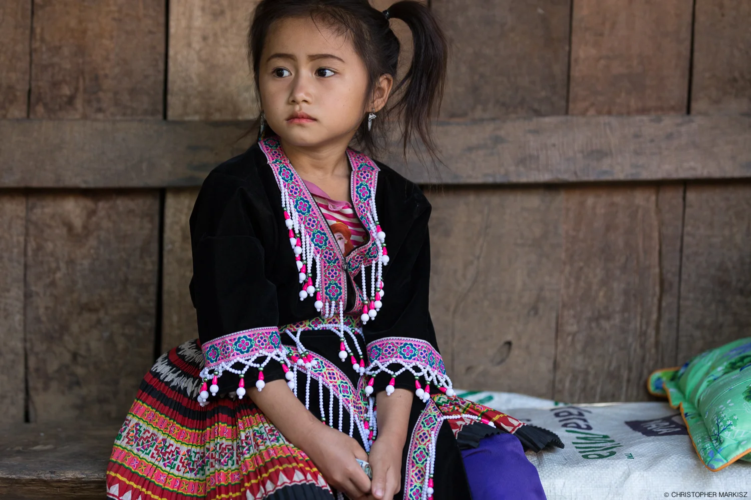 A Hmong girl in traditional dress outside her family's home in a small village near Luang Prabang, Laos.
