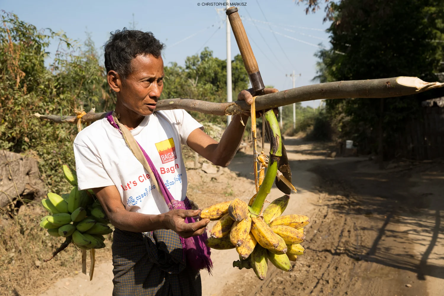 A man walking through a small village in Old Bagan, Myanmar, offers bananas for sale.