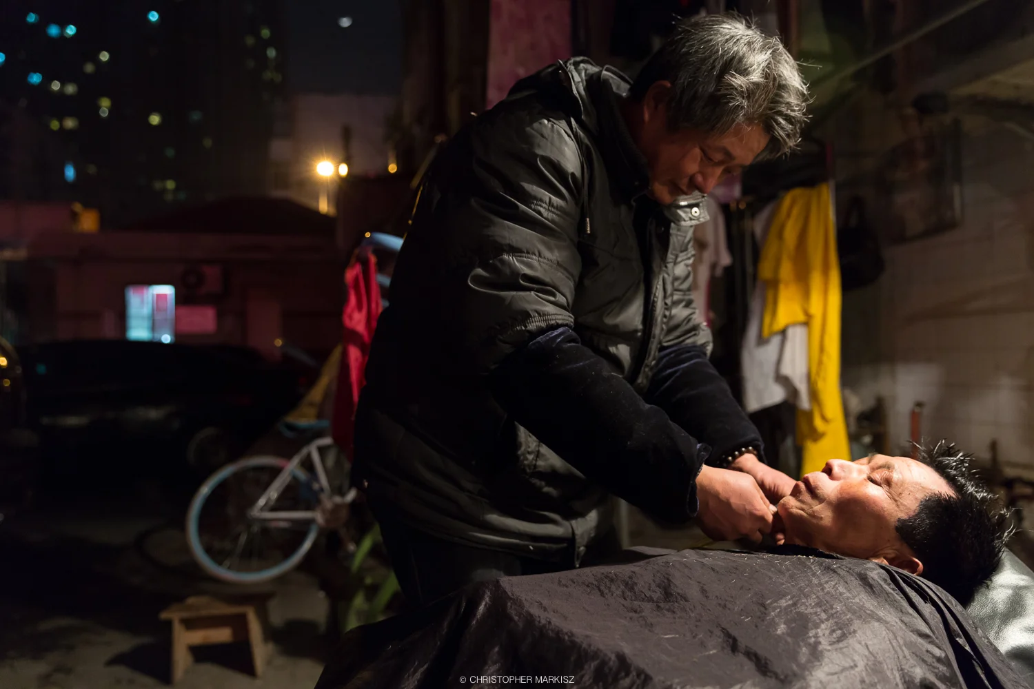 A street barber gives a patron a shave in Shanghai, China.