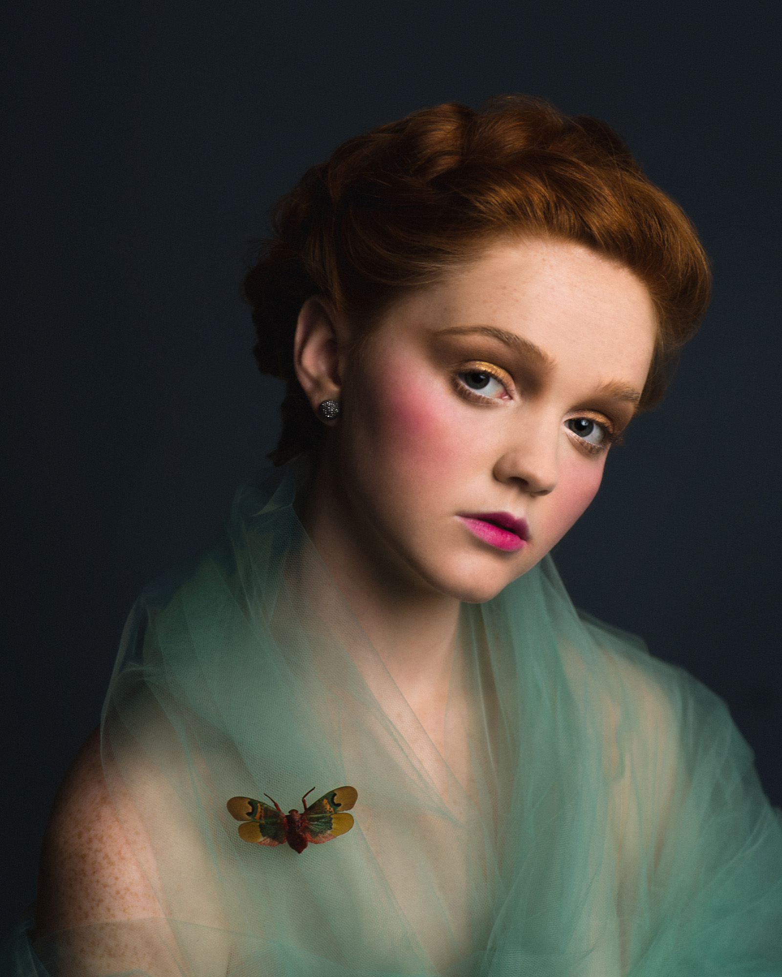 Romantic Victorian inspired studio portrait of a redhead model in tulle with a bright moth. By Sarah Hooker Photography