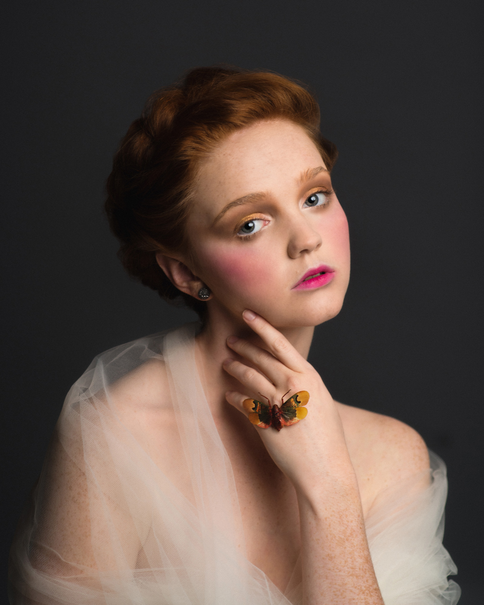 Romantic Victorian inspired studio portrait of a redhead model in tulle with a bright moth. By Sarah Hooker Photography