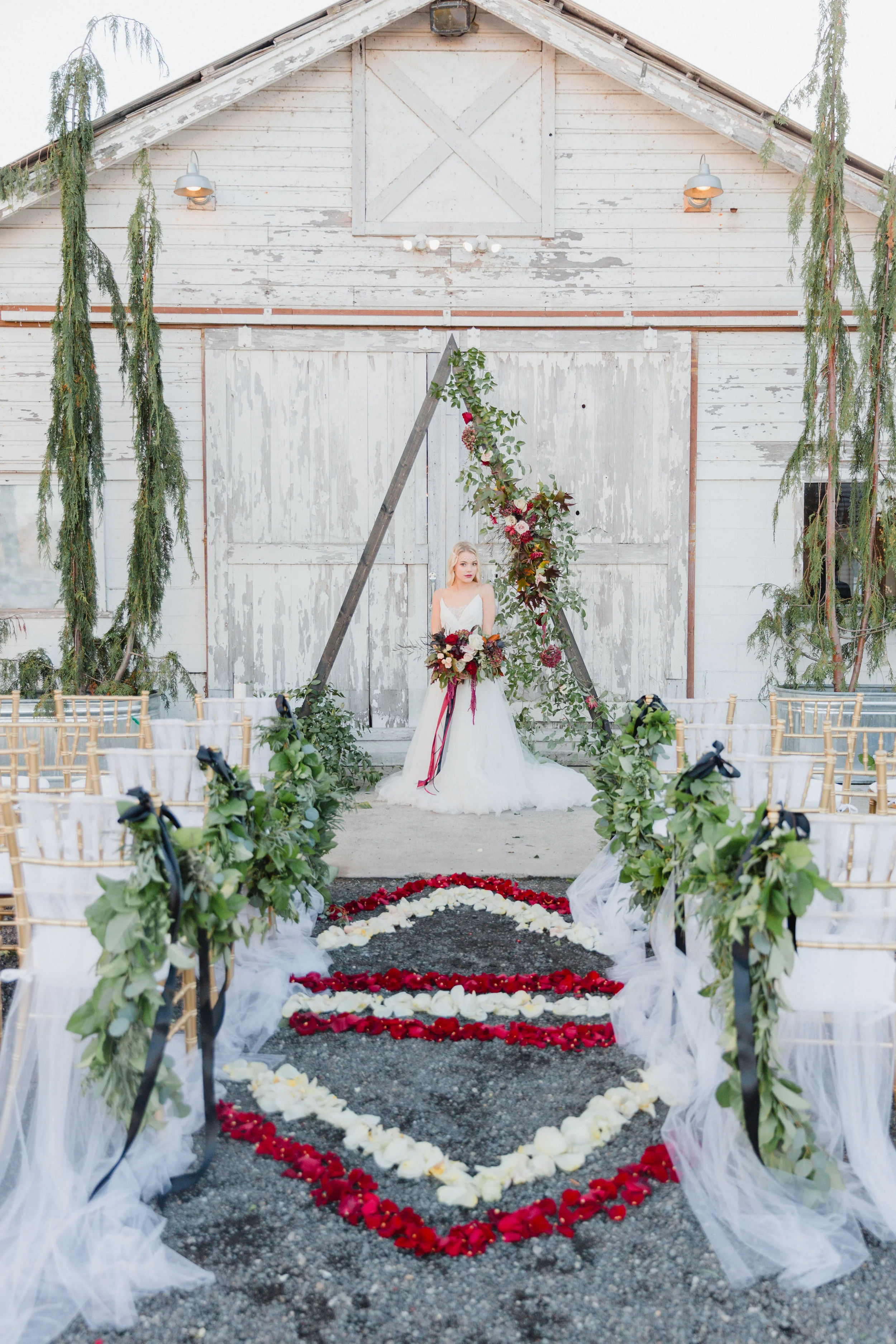 Modern geometric aisle decor with rose petals, garland, and triangle arch by From the Ground Up Floral.