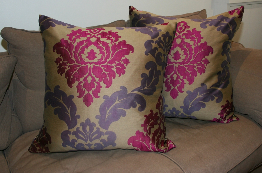 Two cushions, upholstered in an ornate pink and purple fabric