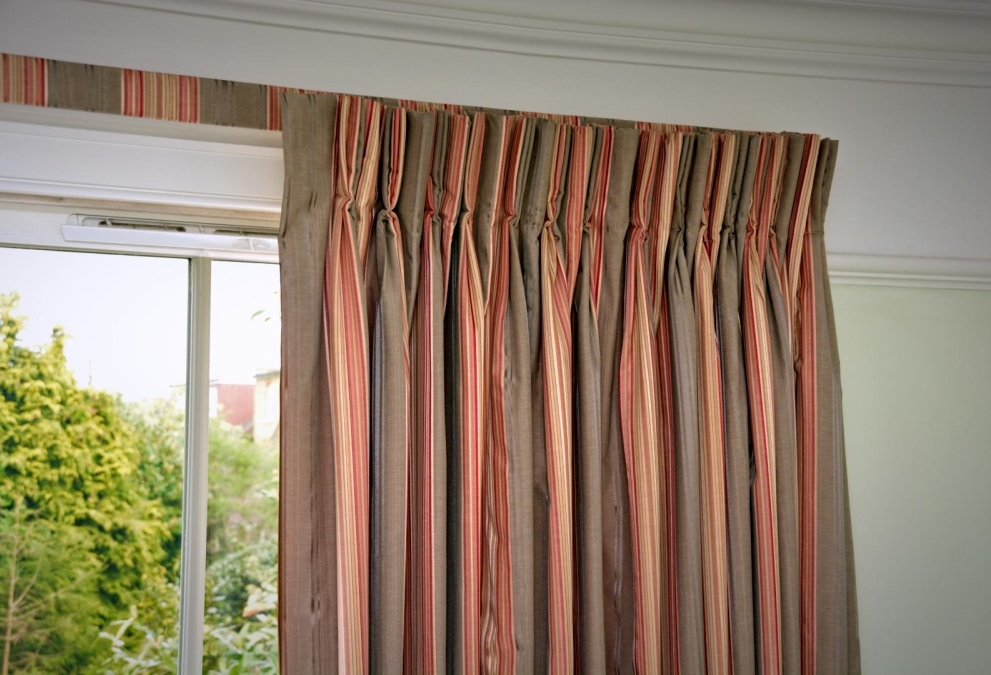 Orange and brown vertically striped curtains with matching, covered lath