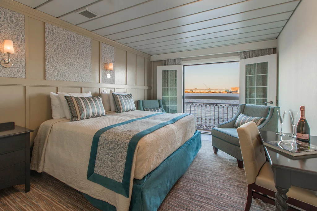 Bedding tucked. Wrinkles minimized. Use only props - champagne & glasses - provided or available to all guests. Windows open for full outside (river cruise) view.
