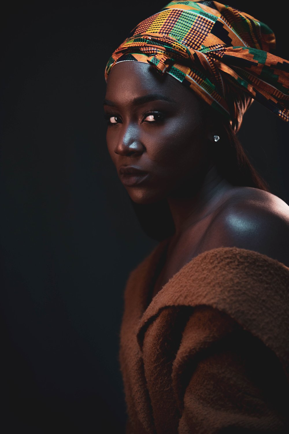Studio portrait of a woman in a patterned headwrap by Imran Stephen