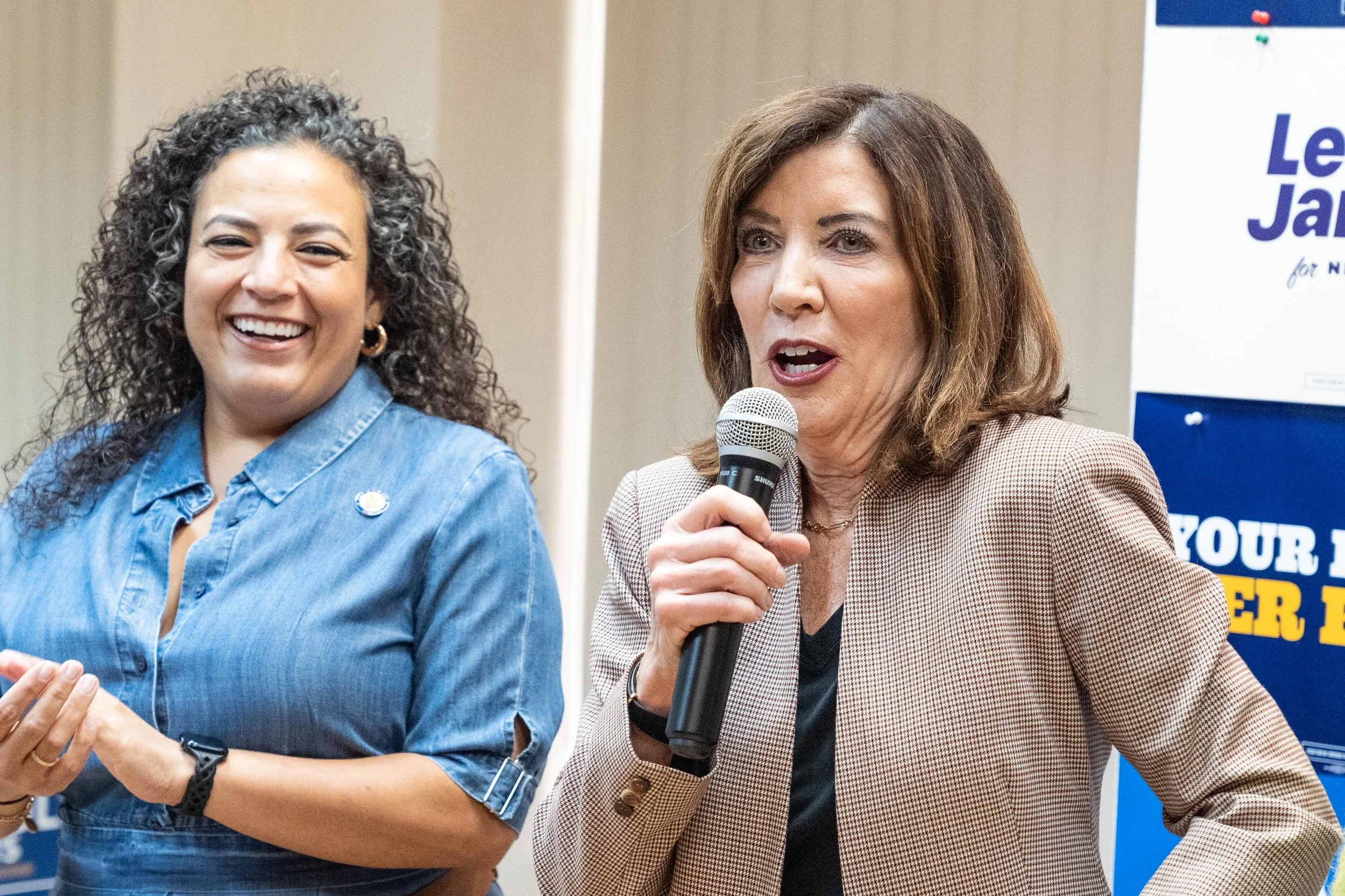 A speaker holds a microphone beside another attendee at a campaign gathering.