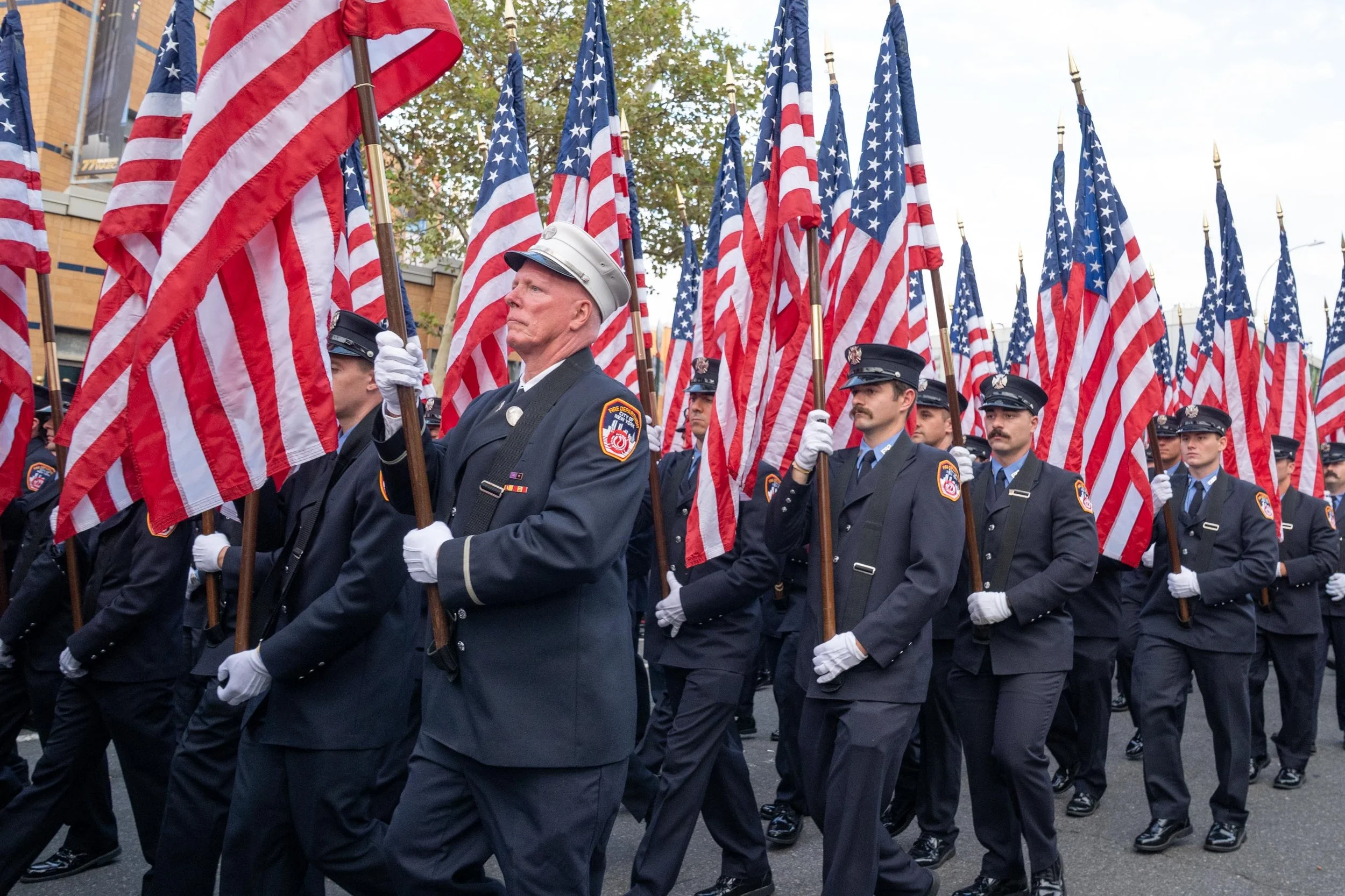 Uniformed FDNY members carry American flags during a memorial procession.
