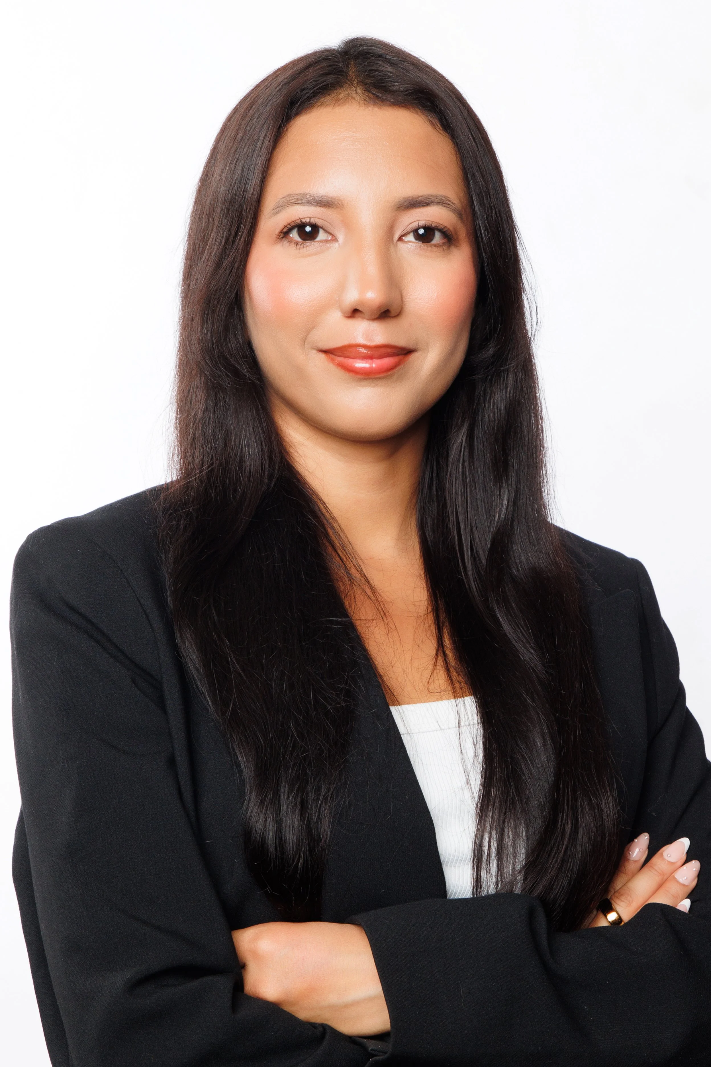 Business headshot of a woman in a black blazer and white top with her arms crossed.