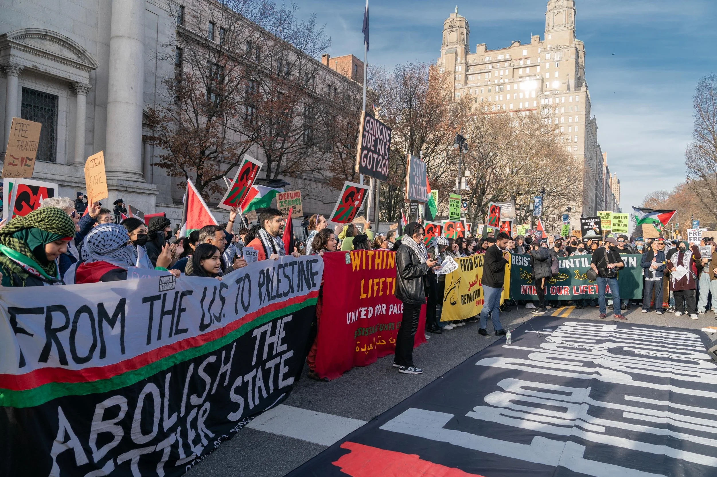 Demonstrators hold Palestinian flags, placards, and banners during a street rally.