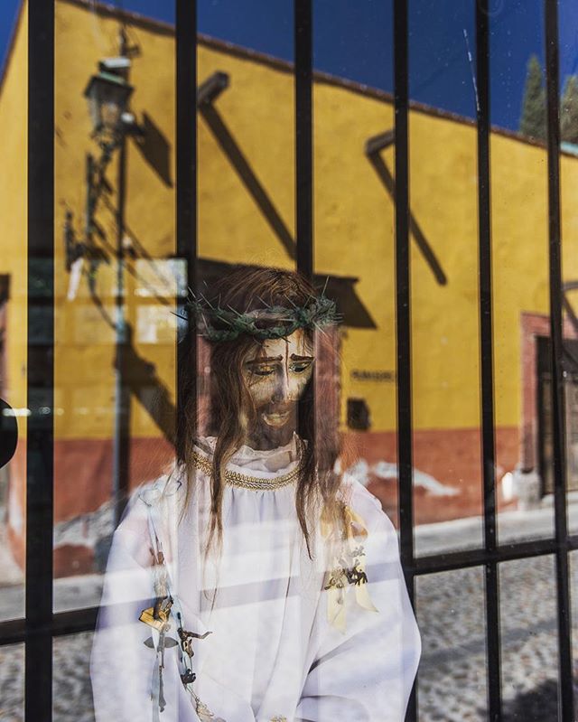 A Jesus statue in a shop window in San Miguel de Allende, relecting the street across.