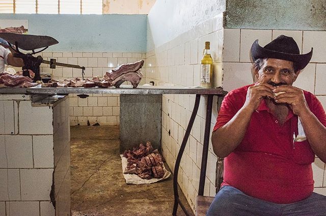 A butcher in a small local market of Santiago de Cuba, enjoying a healthy bite of his pork sandwich.