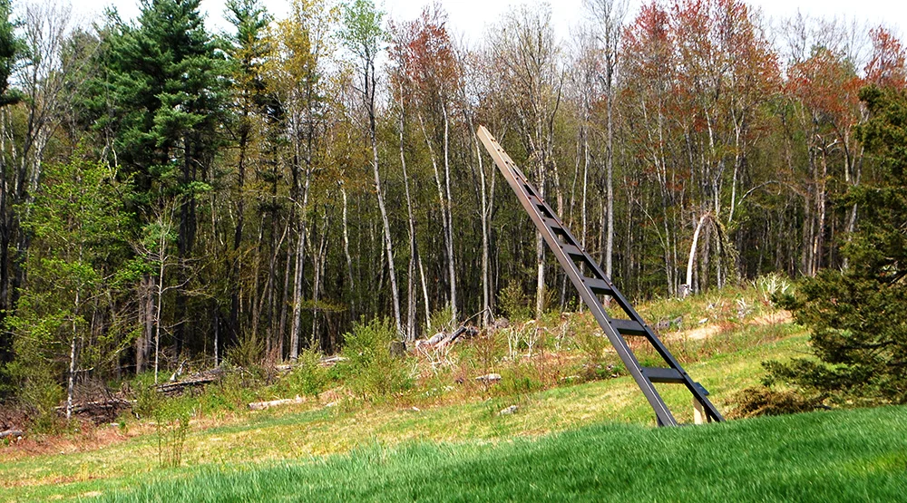   Ladder to Fruitlands  is made from painted steel. 6' 5"height x 2' 8" width at base which recedes to 3" width at top. 8' long steel rails lean at a 51 degree angle over the landscape towards the farmhouse.    Steel Fabrication: Dan Kendall  Special
