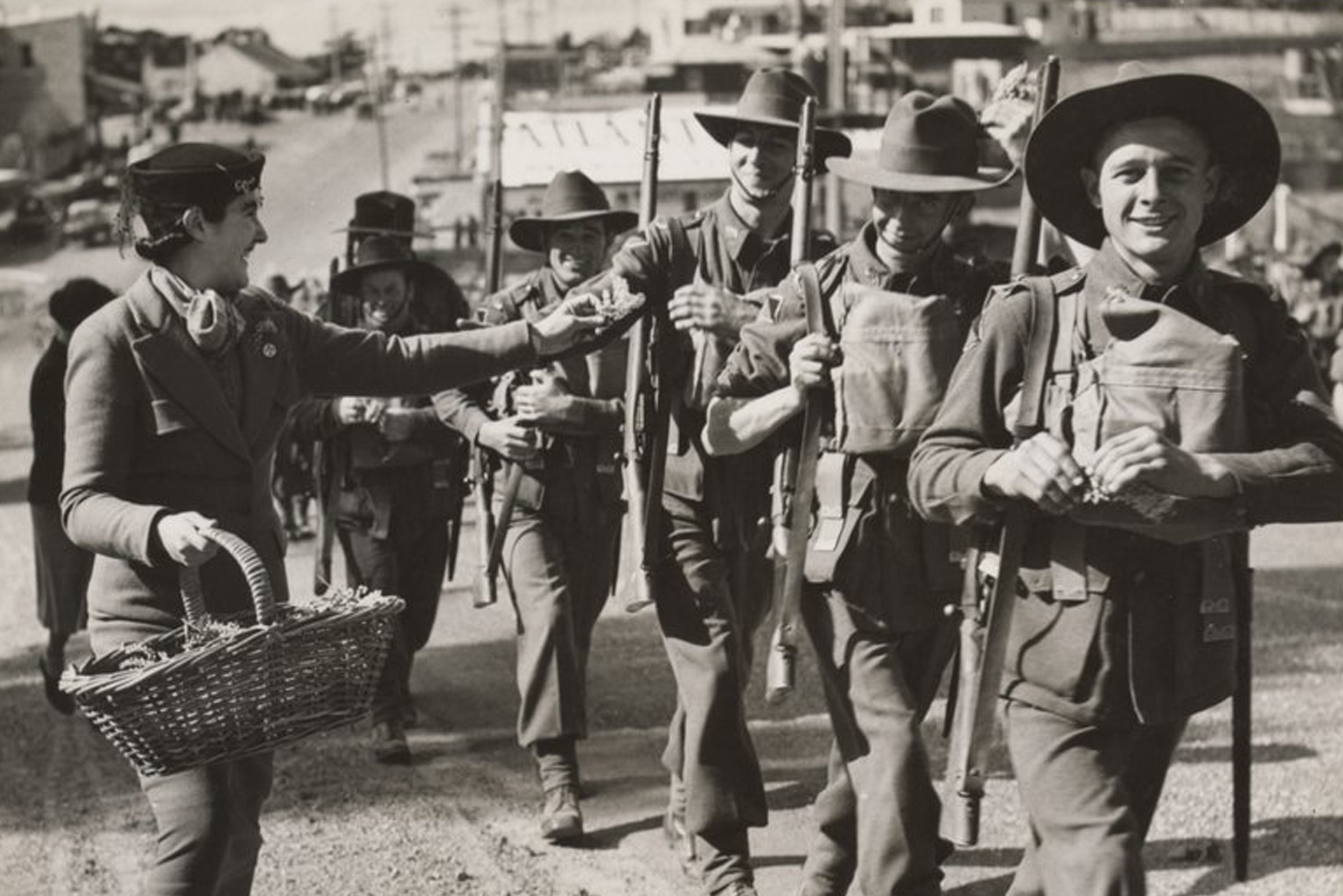  Soldiers during a march to Bathurst. ca. 1940 (World War II). A women is handing out sprigs of wattle to the soldiers as they pass. Image courtesy of Argus Newspaper Collection of Photographs, State Library of Victoria. 