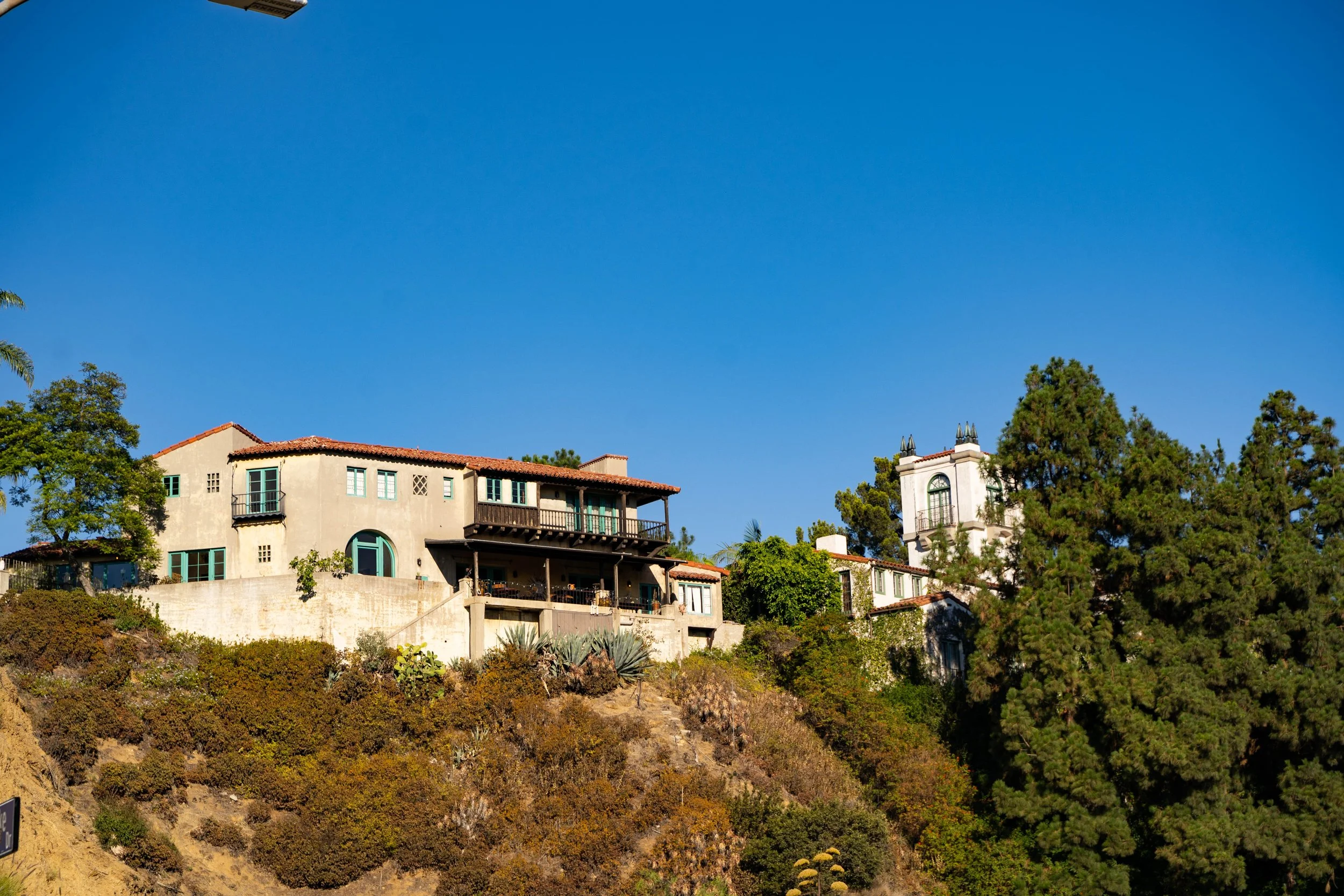 Houses on a hillside with a clear blue sky and green trees.
