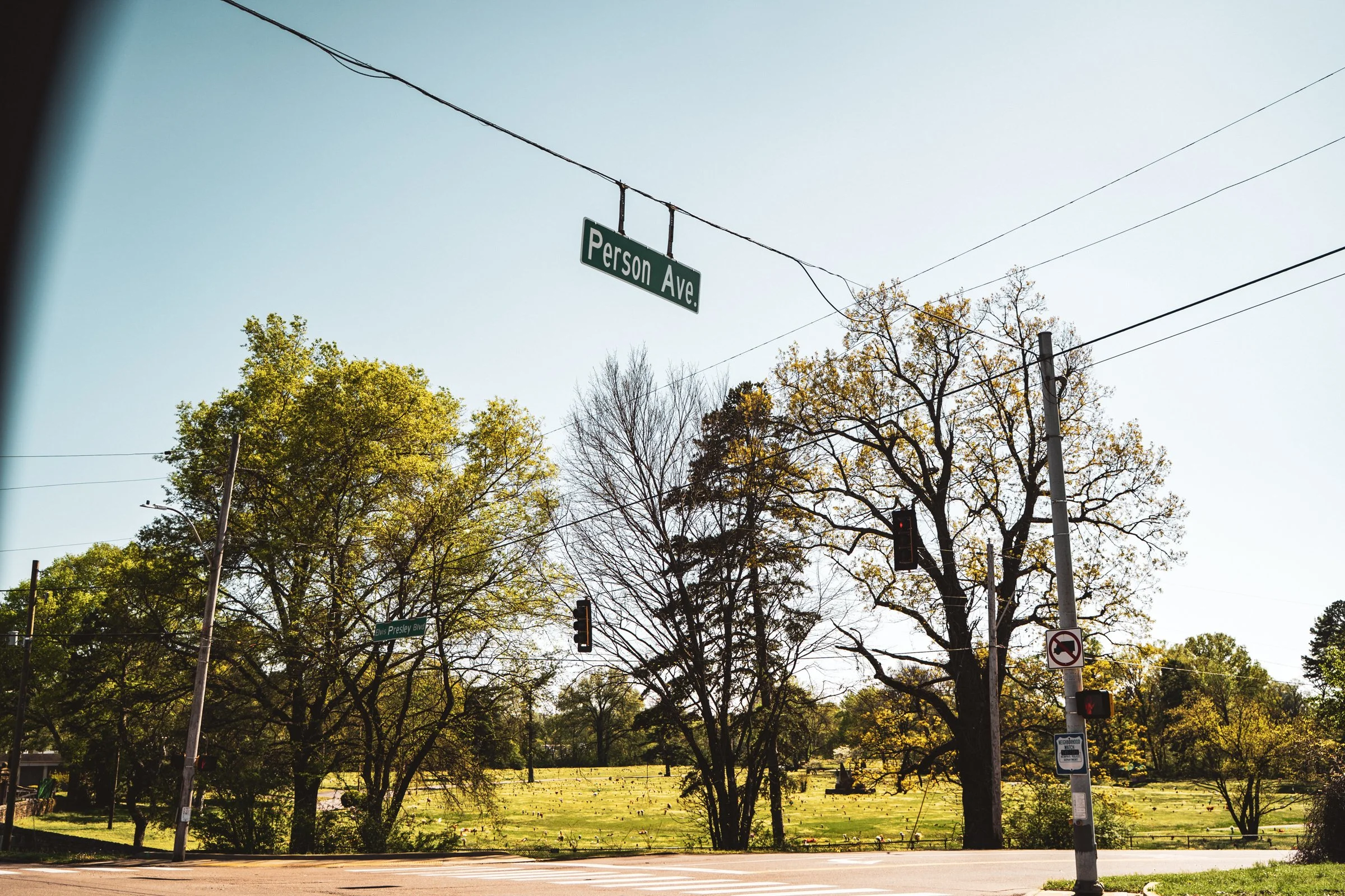 Street view showing traffic light at the intersection of Person Ave and Elvis Presley Blvd with trees and a park in the background, clear sky.