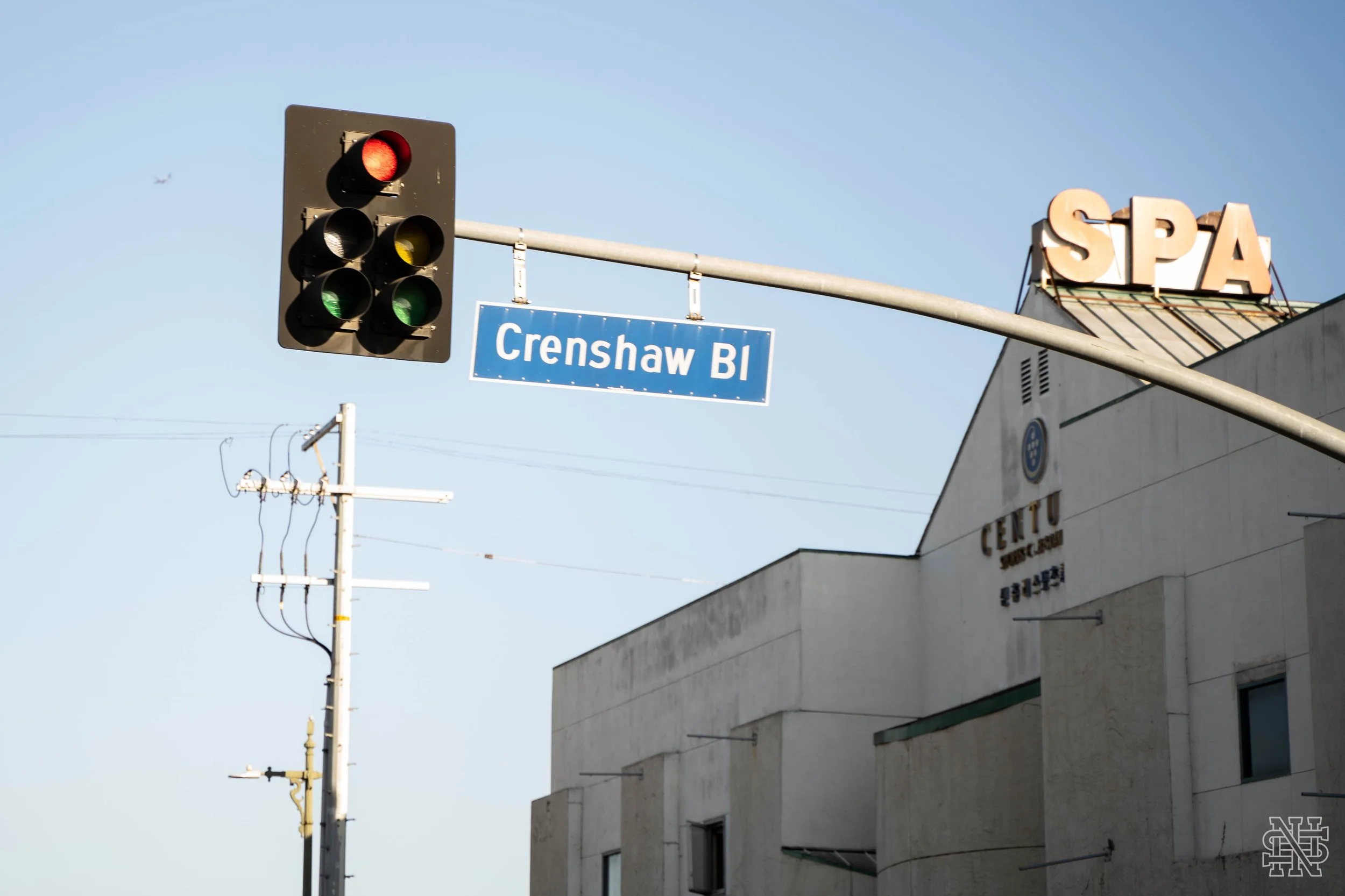Traffic light showing red on Crenshaw Boulevard near a Spokane Public Library building and a spa sign.