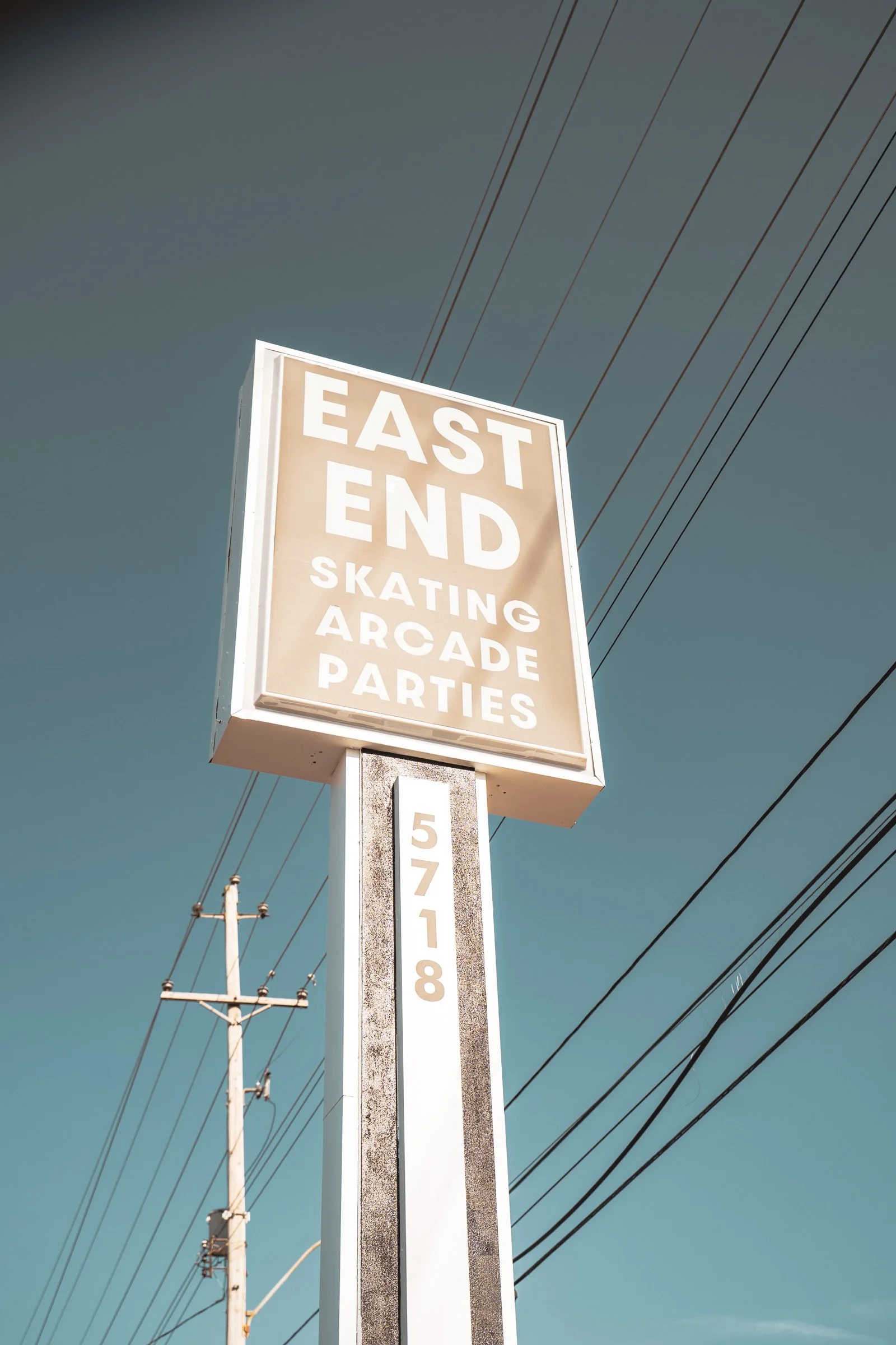 Sign advertising East End skating, arcade, parties with street power lines and a utility pole in the background.
