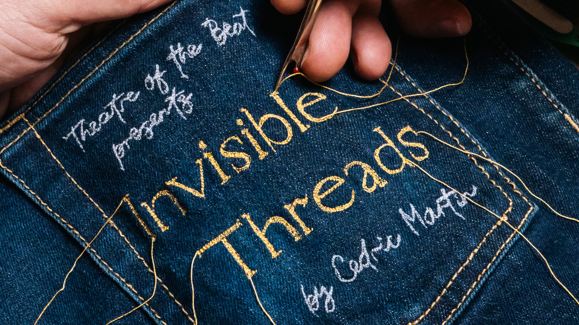 A close up of the play's name "Invisible Threads" stitched into a pair of jeans.