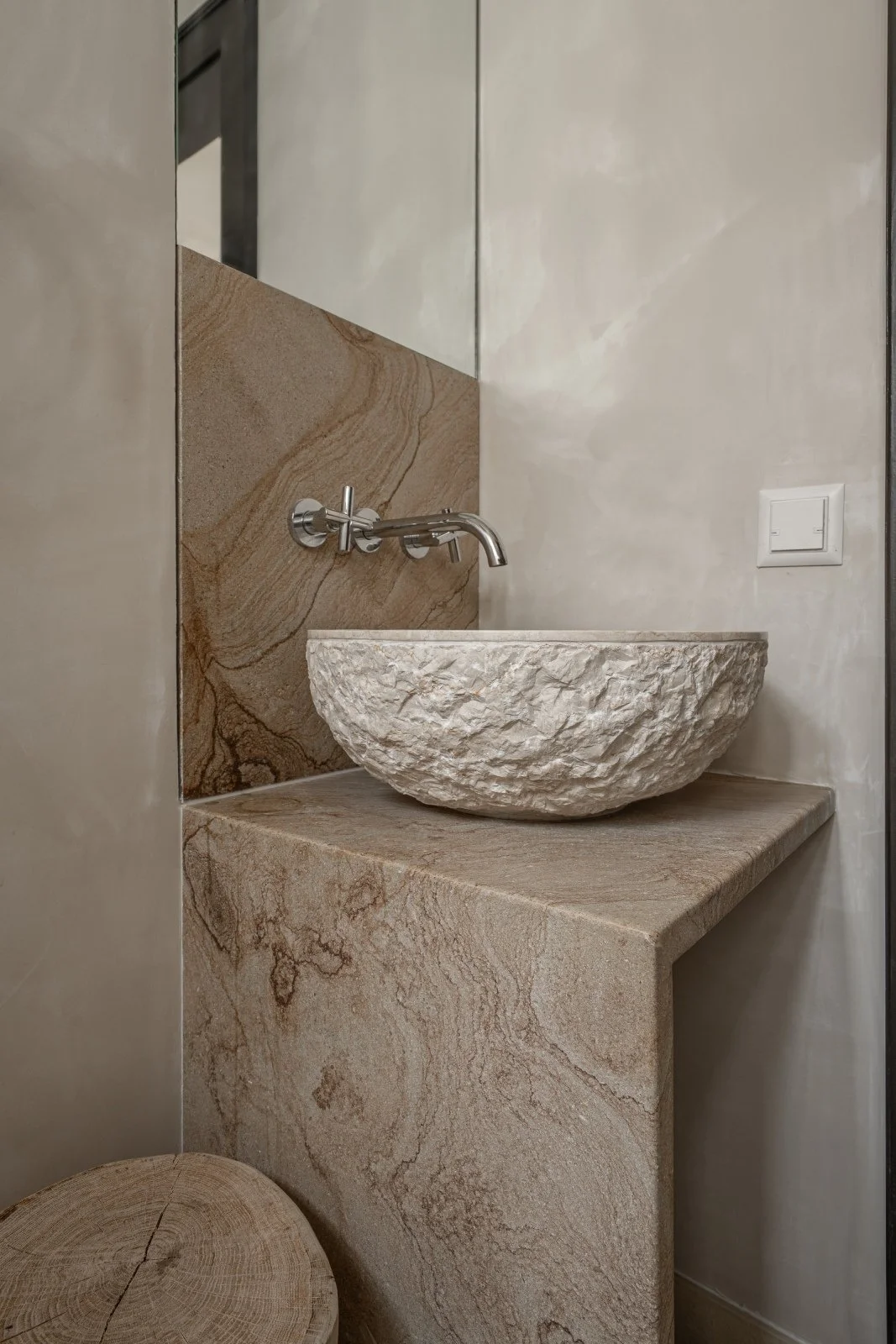 Sculptural stone basin and natural stone vanity in the pool and wellness area.
