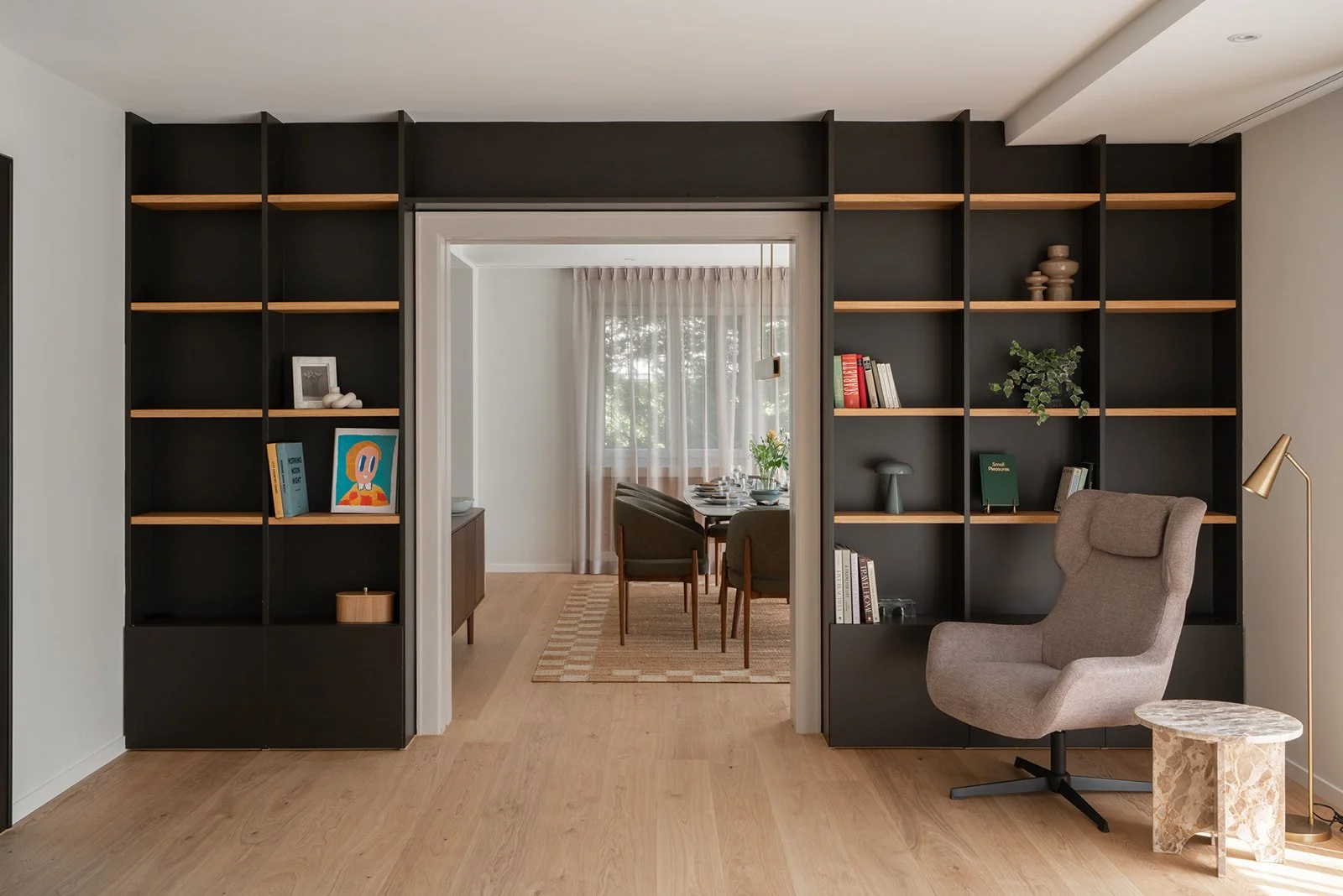 Living room with black built-in shelving, oak details and a reading chair at Landhaus Ennetmoos.