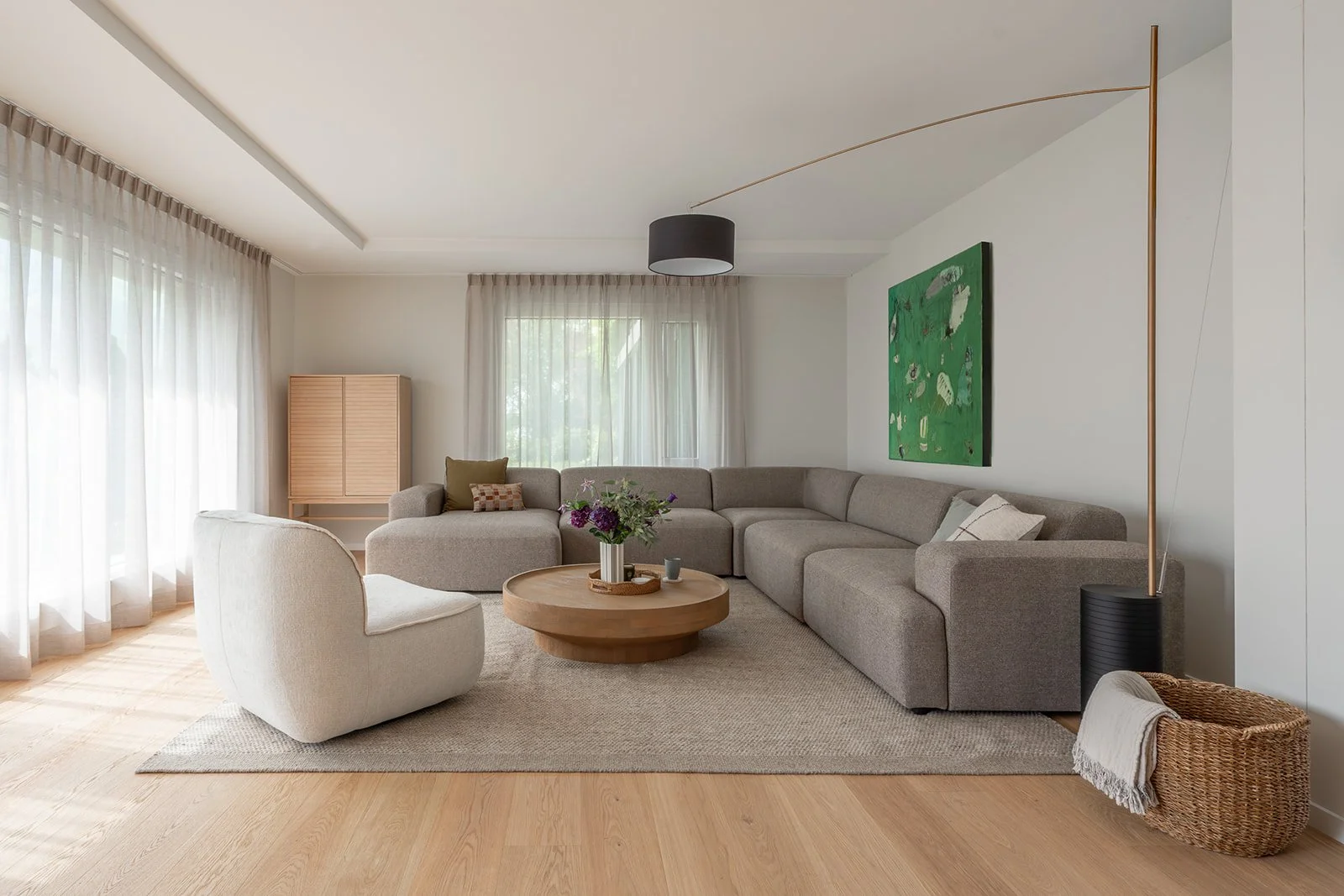 Landhaus Ennetmoos living room with modular sofa, lounge chair, artwork and soft natural light.